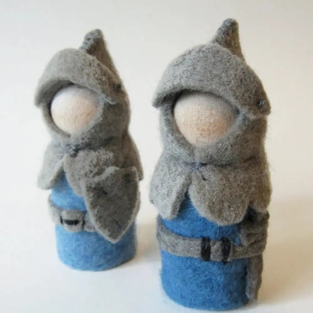 Two felted dolls dressed in gray hooded cloaks and blue outfits on a white background