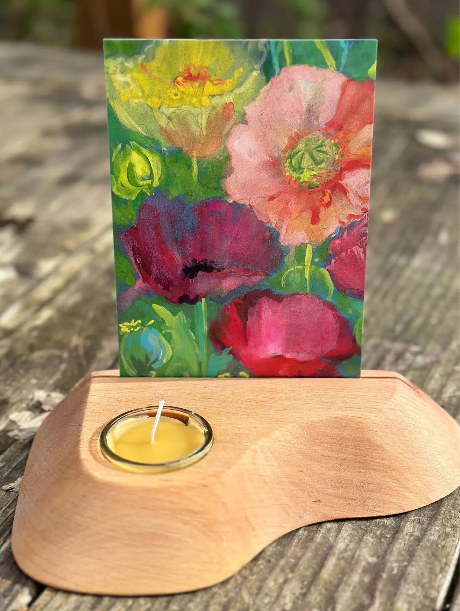 Floral painting on a wooden candle holder with a lit candle.