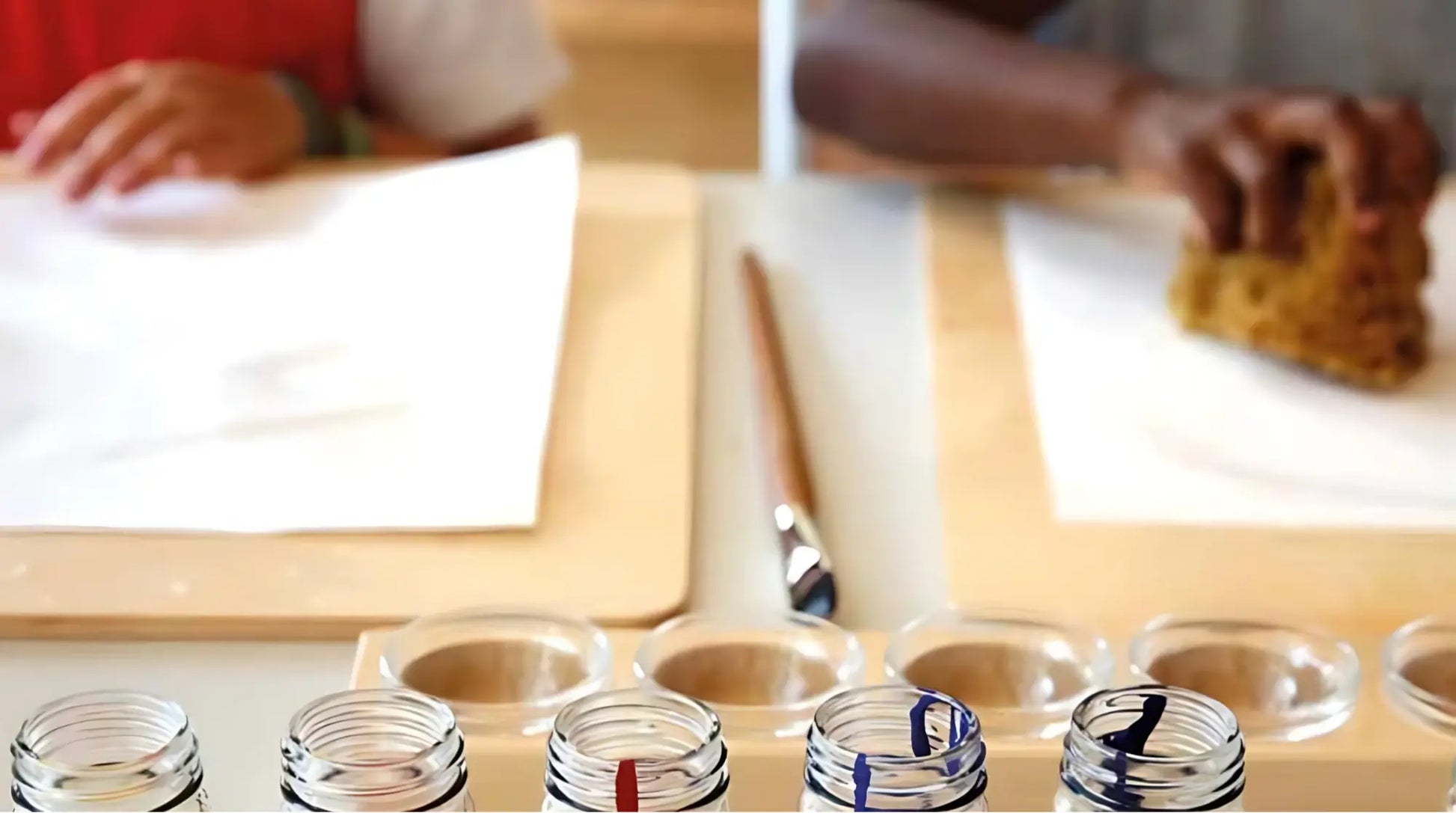 Table with children's hands with watercolor paper on a wooden paint board