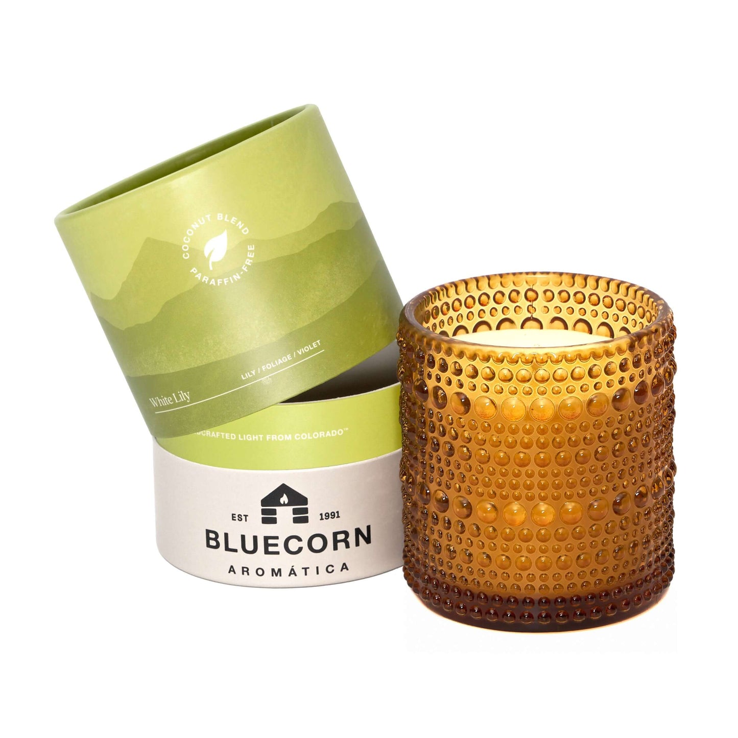 Brown textured candle in front of a green and white Bluecorn Aromatica packaging on a white background