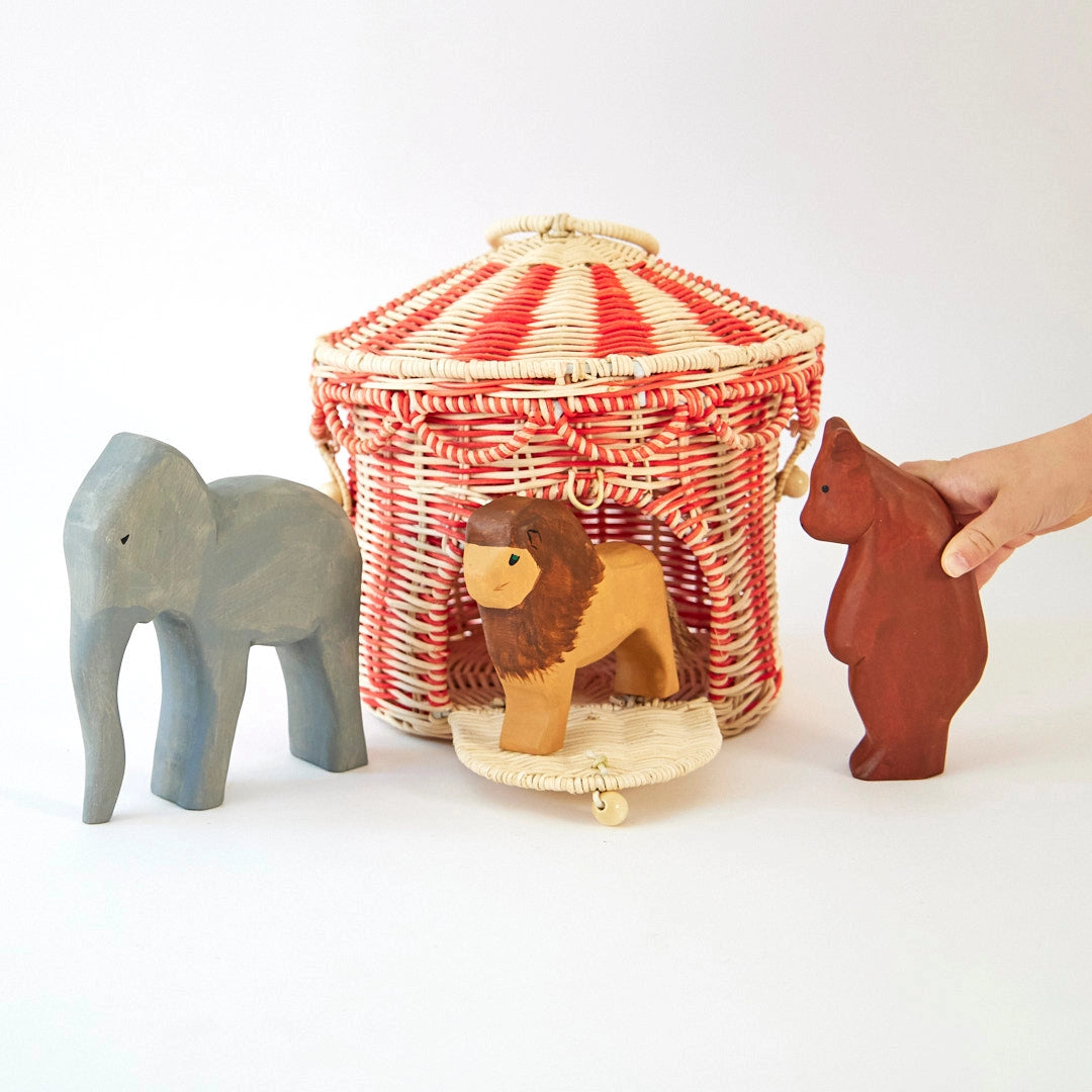 Wooden toys including an elephant, lion, and bear with a wicker basket on a white background