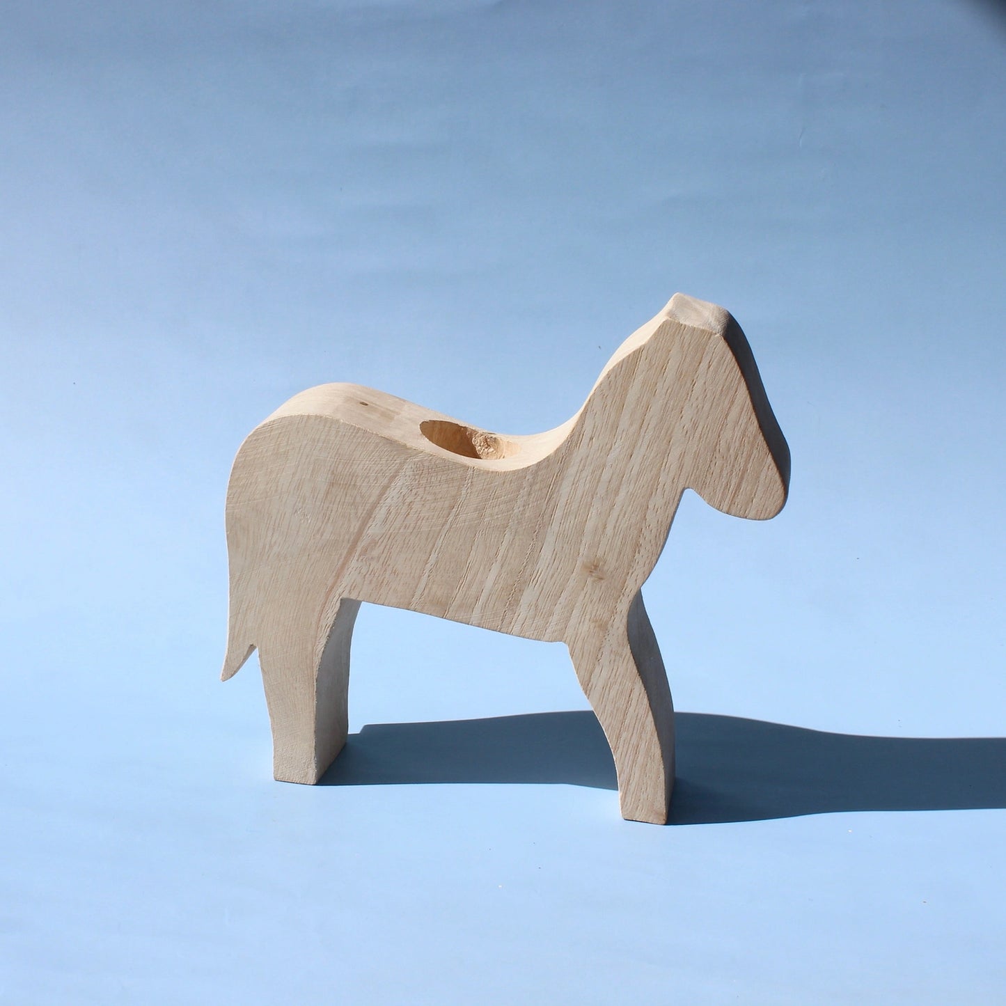 Wooden horse figure on a light blue background for imaginary play toys