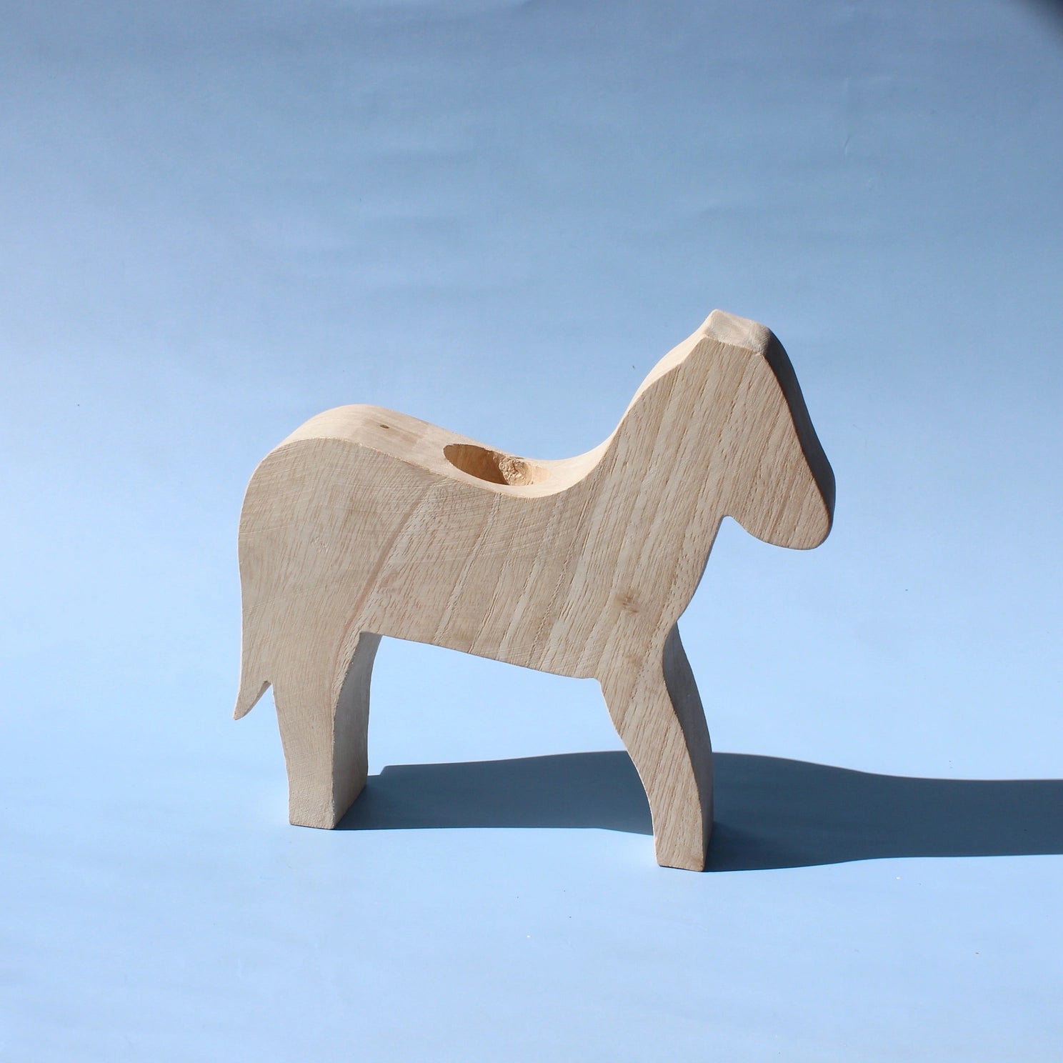 Wooden horse figure on a light blue background for imaginary play toys