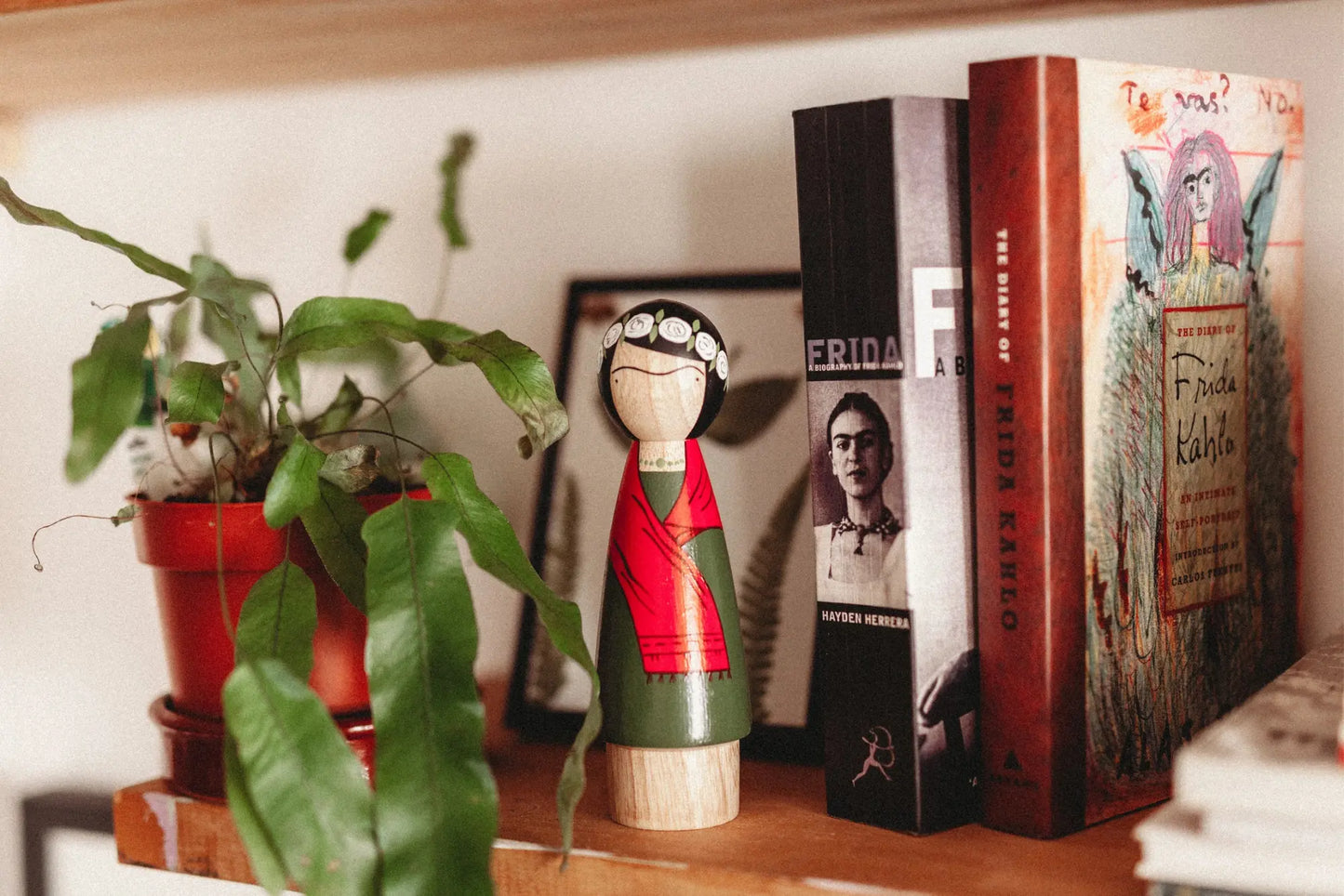 Bookshelf with books, a plant, and a figurine on a wooden shelf.