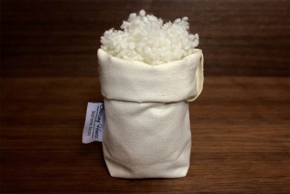 Small bag filled with white wool bolus for dollmaking on a wooden surface