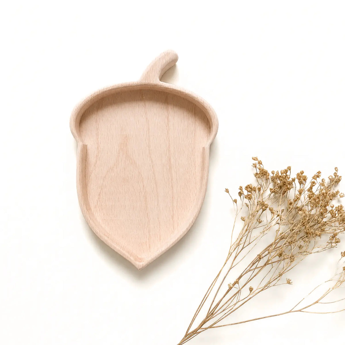 Acorn-shaped solid beech wood nature table tray with dried flowers on a soft neutral background.