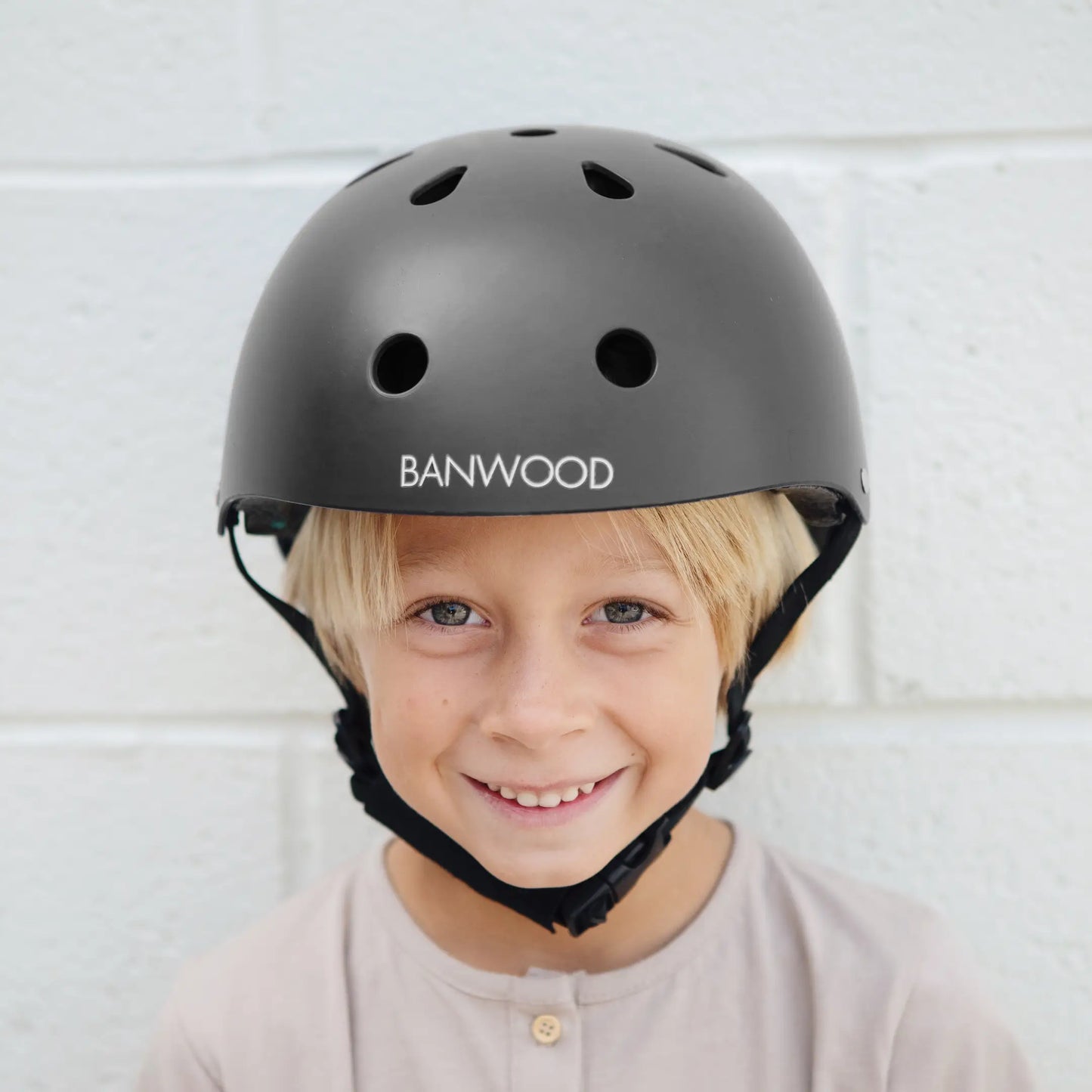 Child wearing a black helmet with Banwood branding against a light background