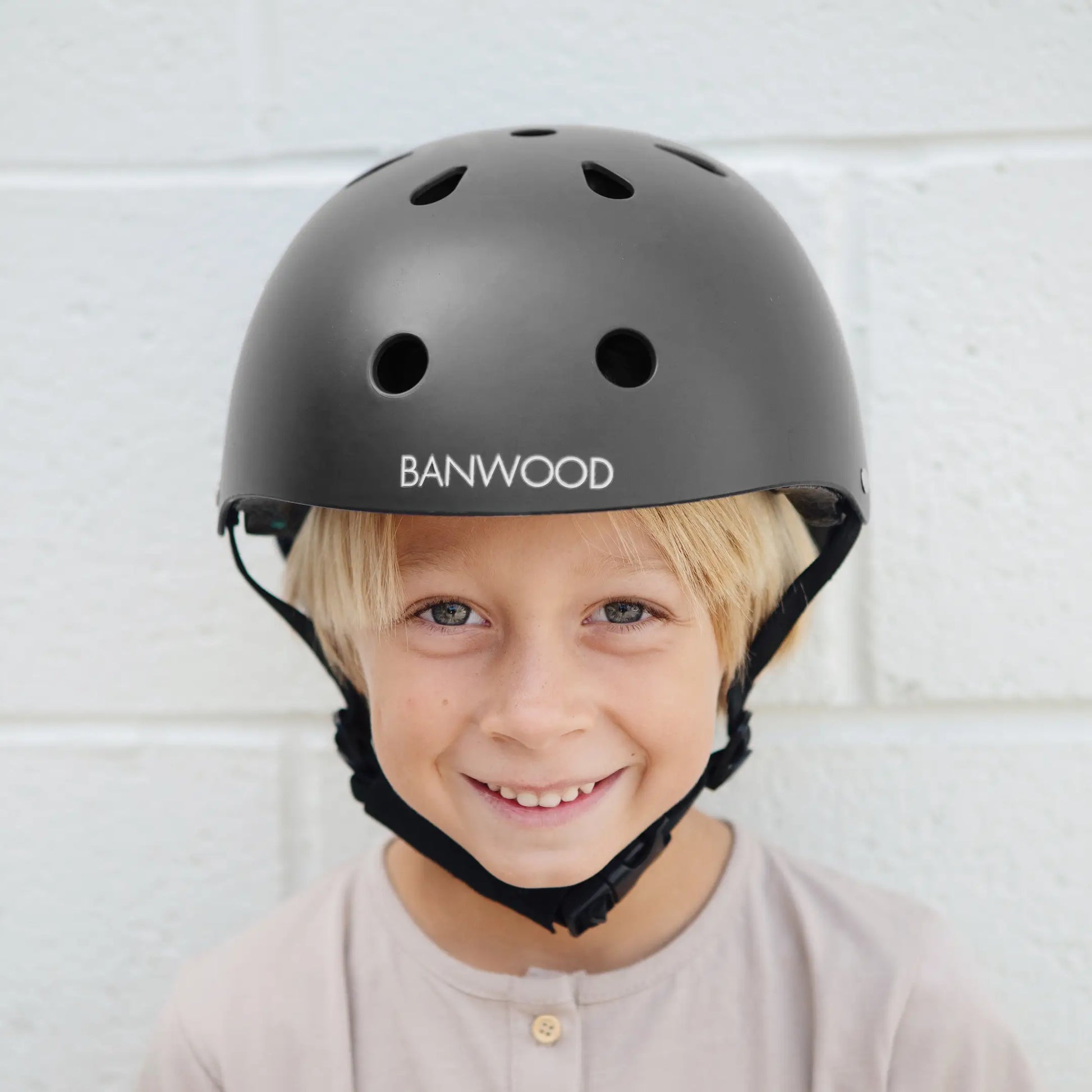 Child wearing a black helmet with Banwood branding against a light background