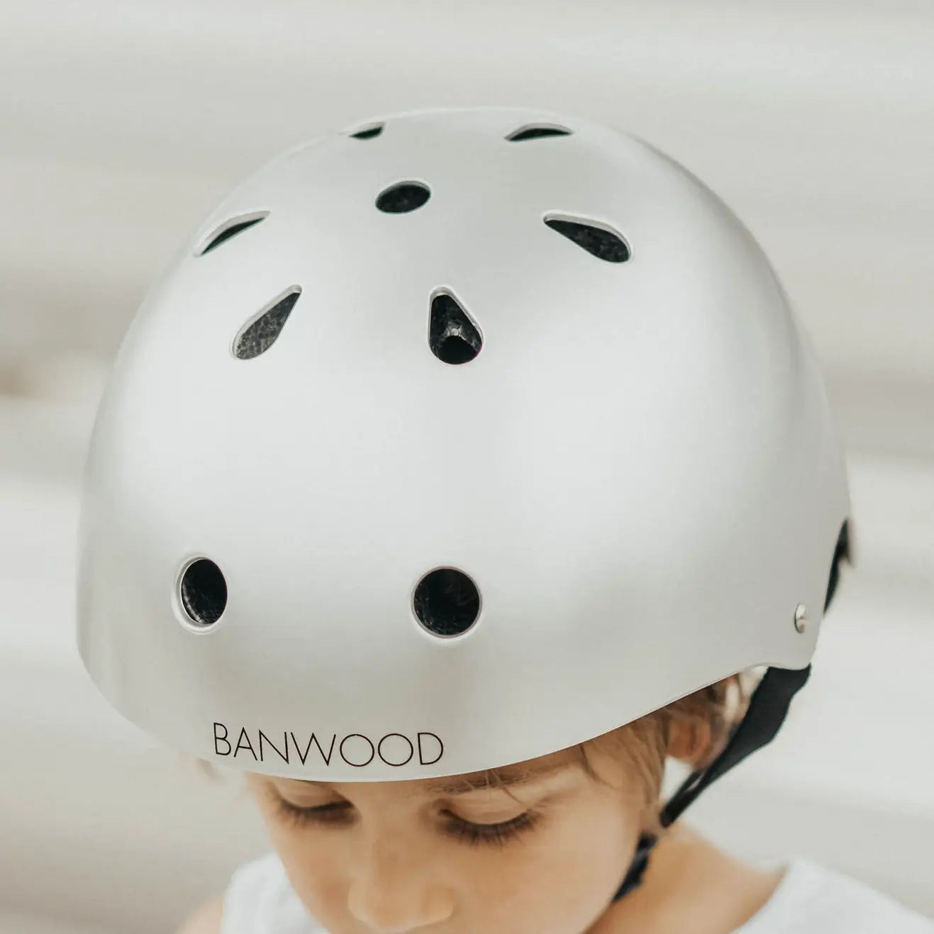 Child wearing a light chrome helmet with BANWOOD branding on a light background