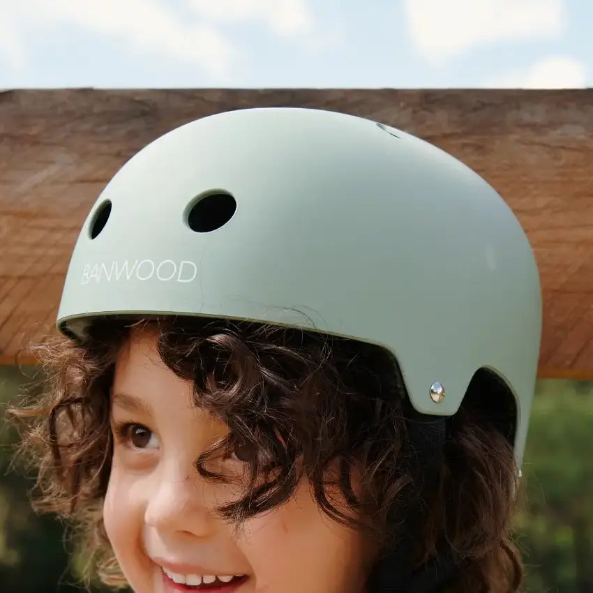 Child wearing a green helmet with BANWOOD branding outdoors.