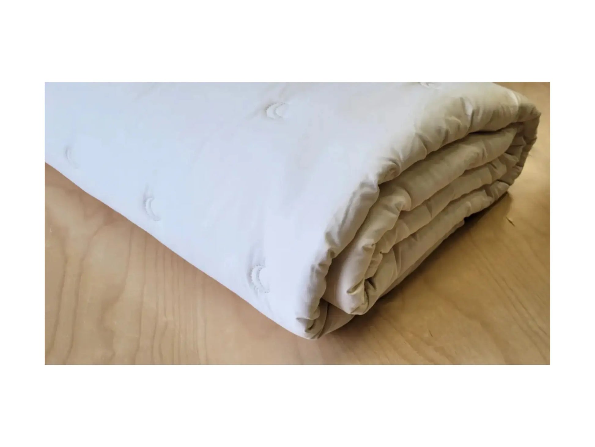 Folded edge of alpaca wool comforter resting on surface showing thickness and natural cotton texture