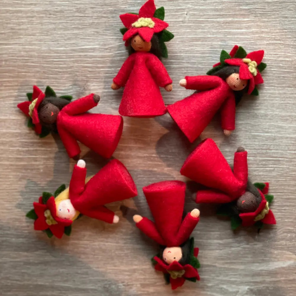 Set of red dolls with floral crowns on a wooden surface