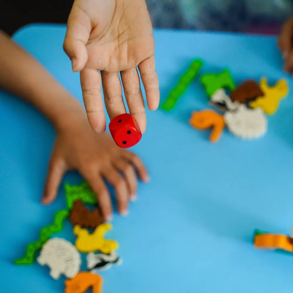 Child rolling wooden die in Animal Upon Animal stacking game