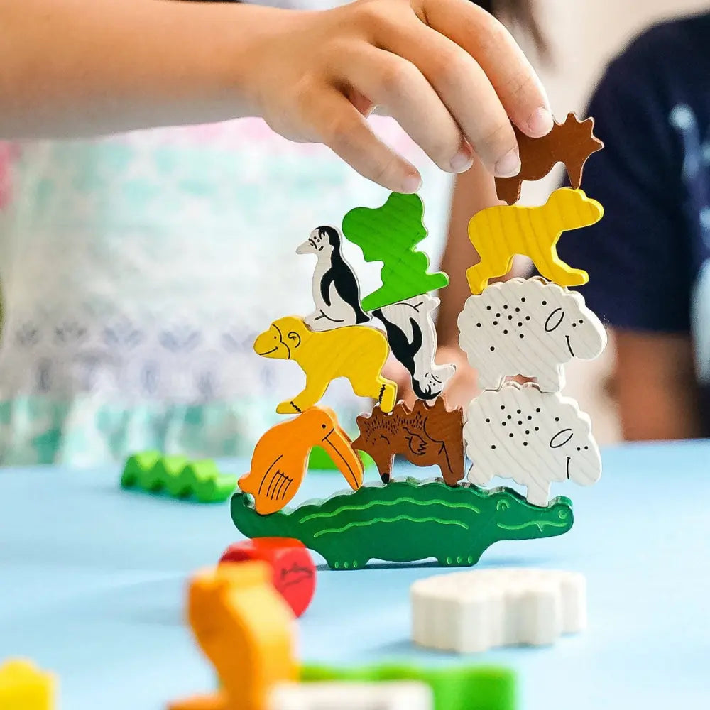 Child stacking wooden animal pieces in Animal Upon Animal balance game