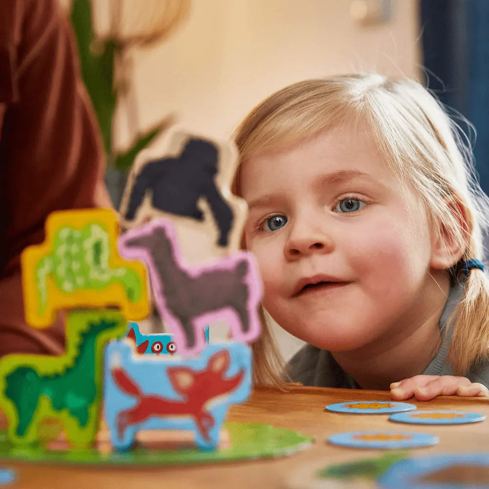 Toddler stacking wooden animal pieces in Animal Upon Animal Junior game