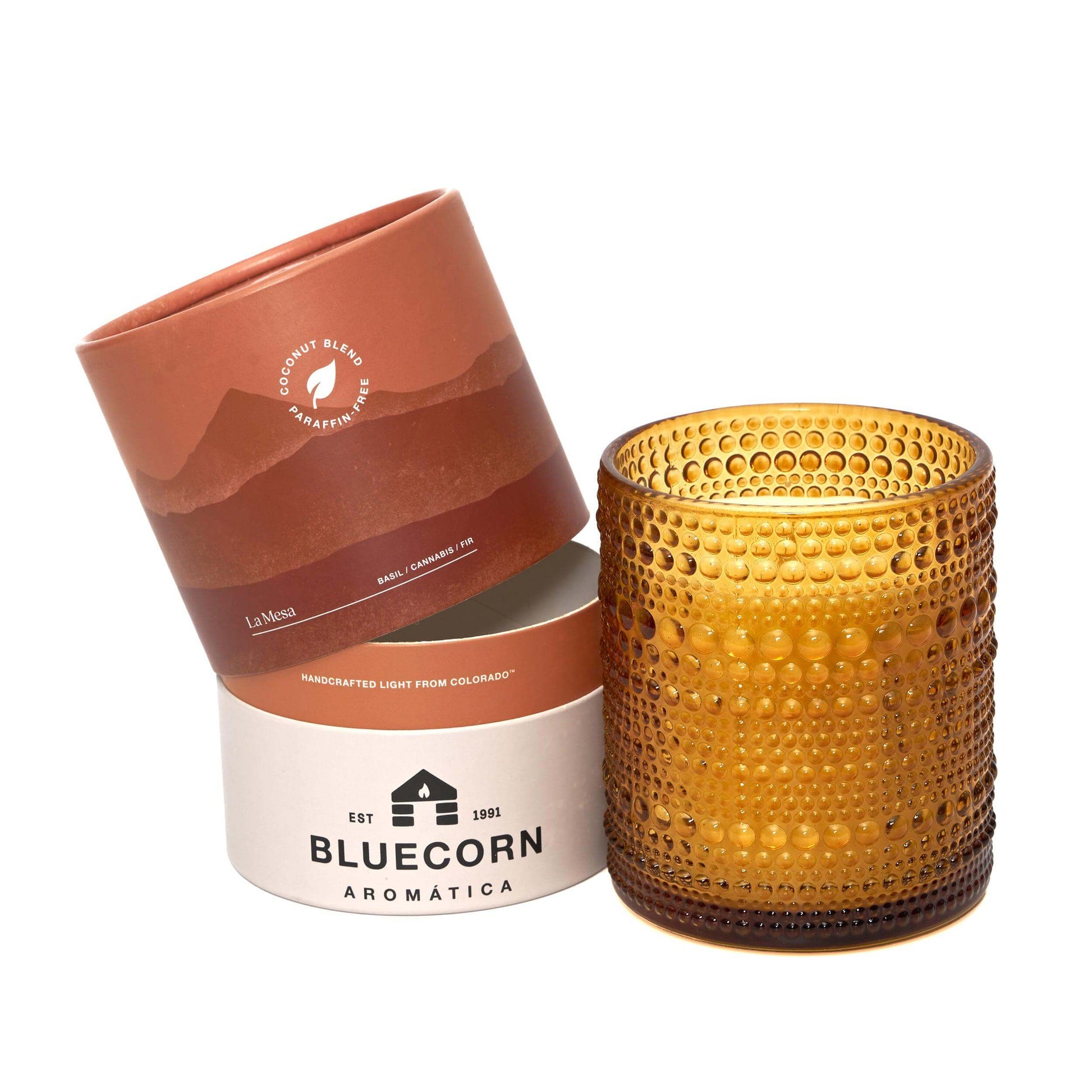 Amber glass candle with textured surface and 'Bluecorn Aromática' packaging on a white background