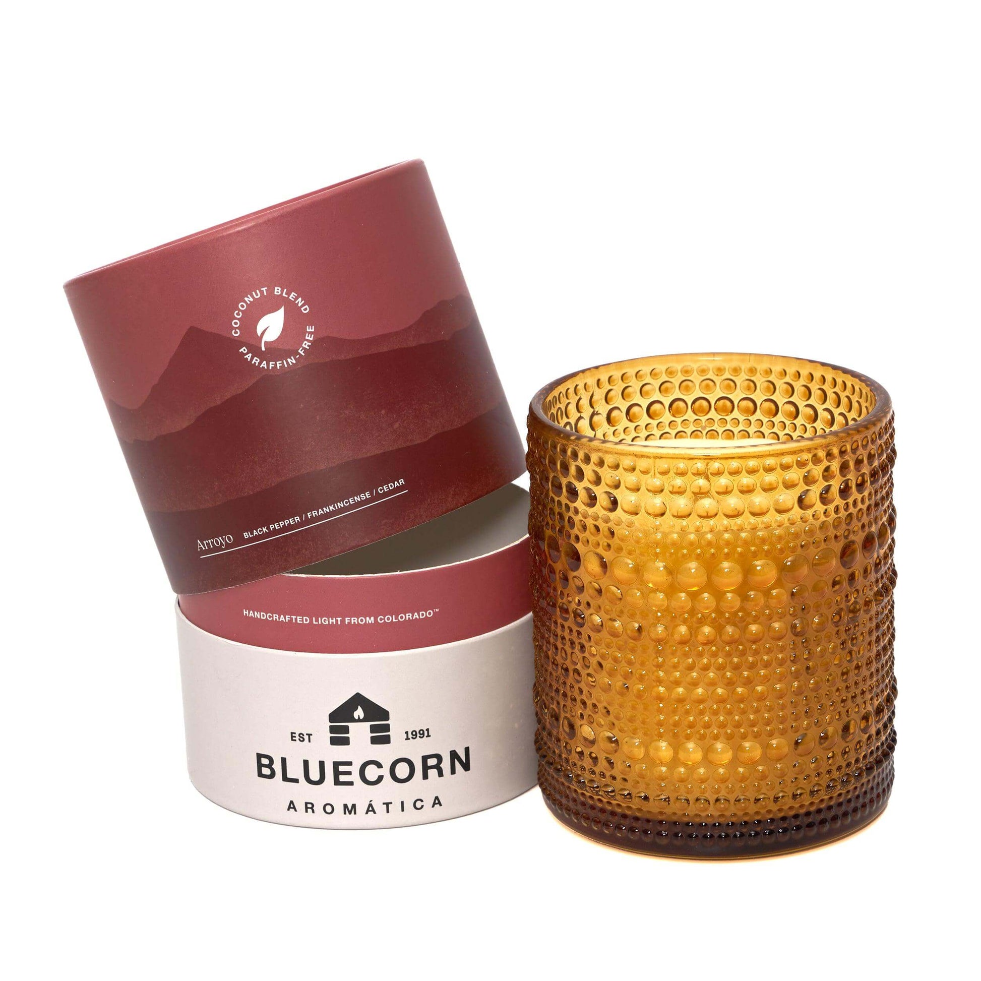 Gold textured candle and two cylindrical containers with 'Bluecorn Aromática' branding on a white background