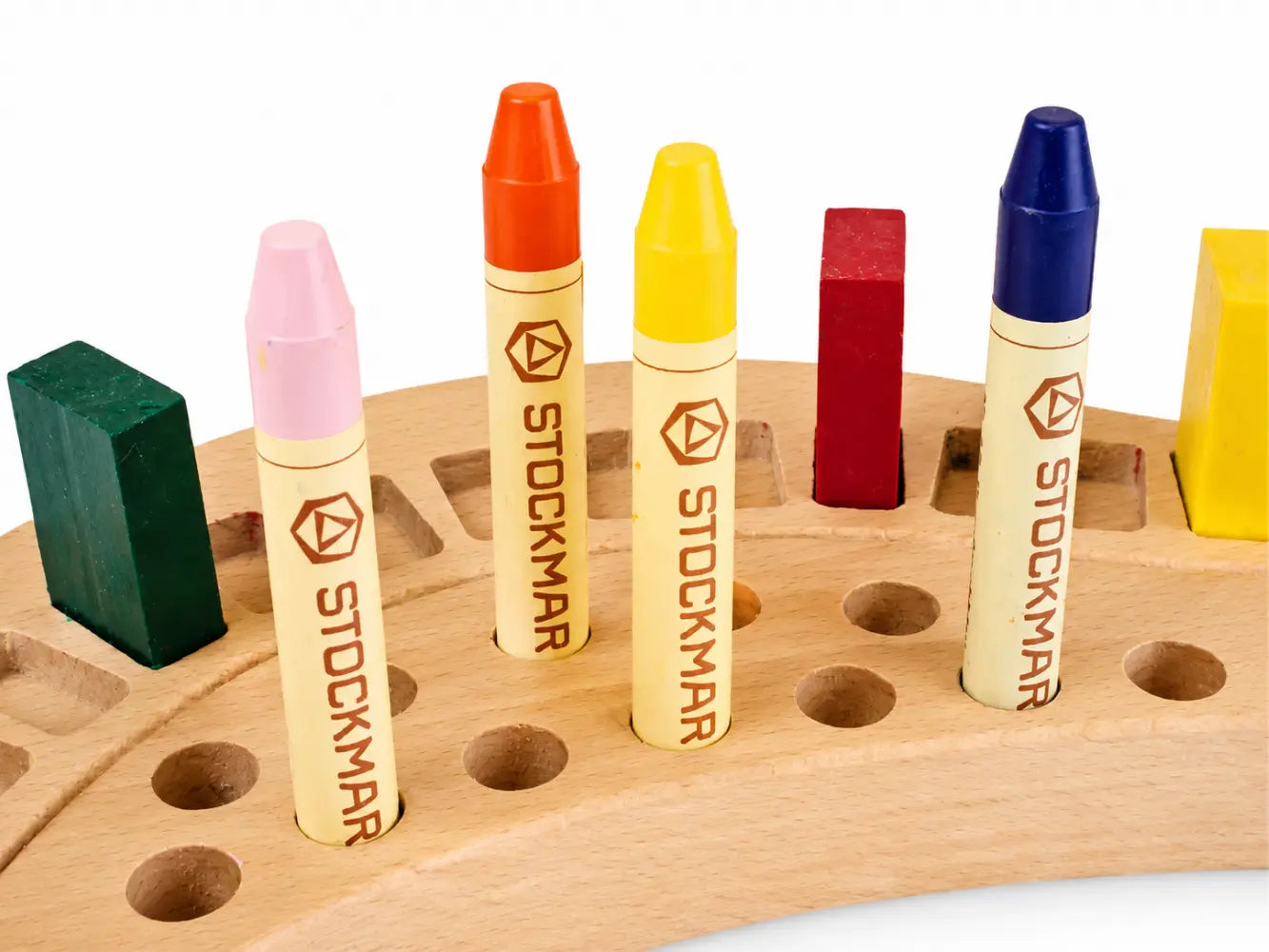 Set of Stockmar crayons in various colors on a wooden holder.
