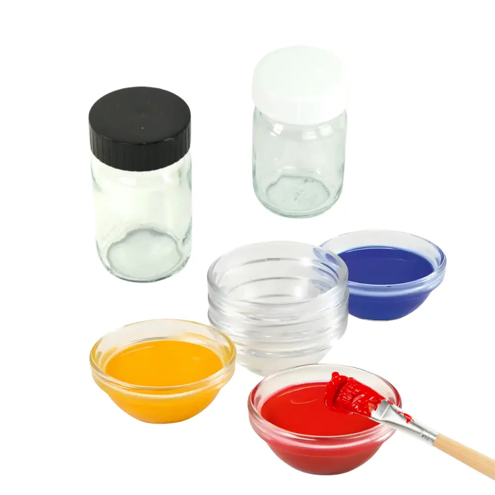 Set of small glass containers with colorful liquids and a brush on a white background