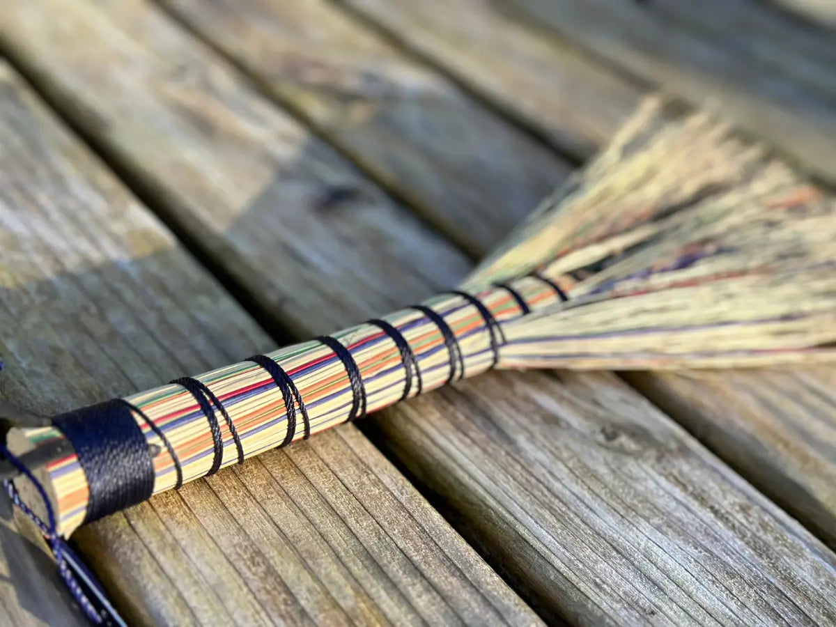 Broom with multicolored bristles on a wooden surface