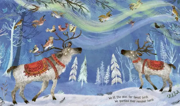 Two reindeer in a snowy forest with birds perched on their antlers against a blue sky.