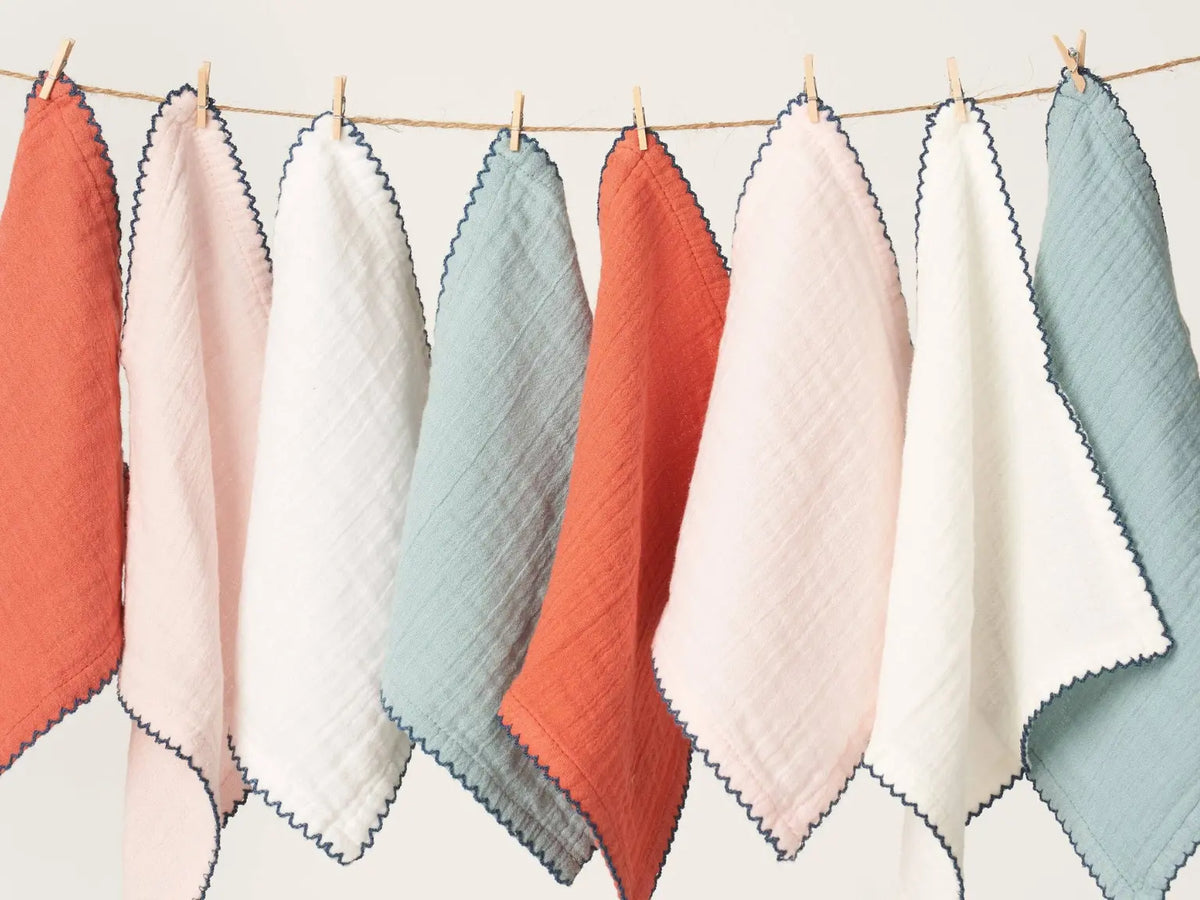 Stack of soft cotton baby washcloths with scalloped edging hanging along a clothesline