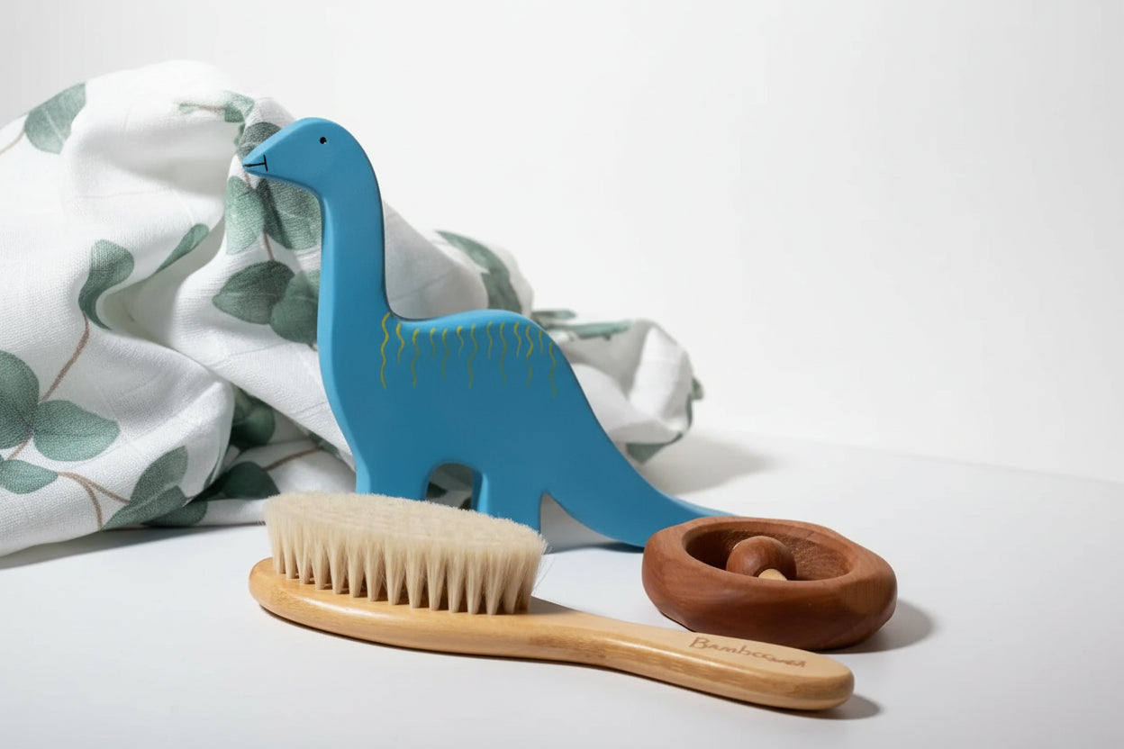 Blue dinosaur-shaped toy, wooden baby hair brush, and wooden toy on a wooden surface 