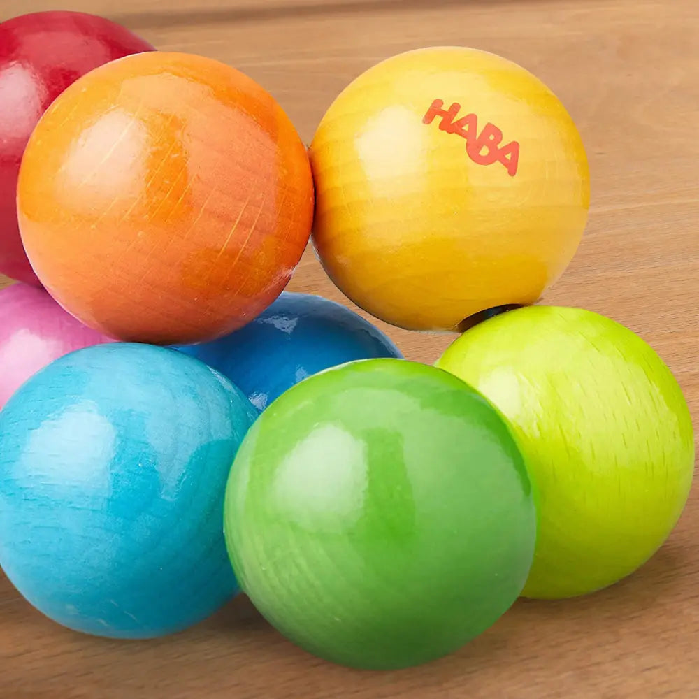 Colorful wooden balls with 'HABA' branding on a wooden surface