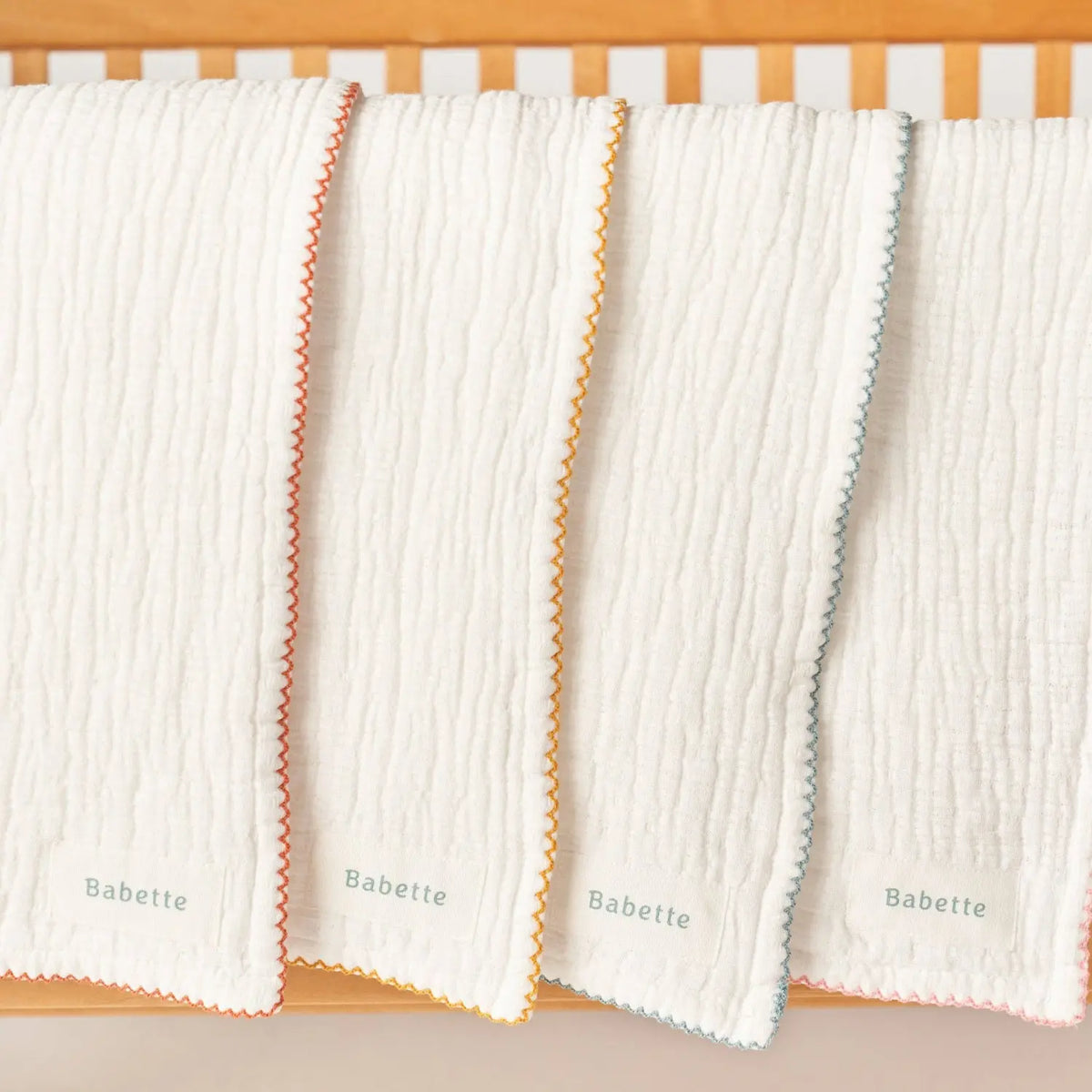 Babette plush cotton baby towels with colorful scalloped trim, made from OEKO-TEX Standard 100 cotton hanging in a row