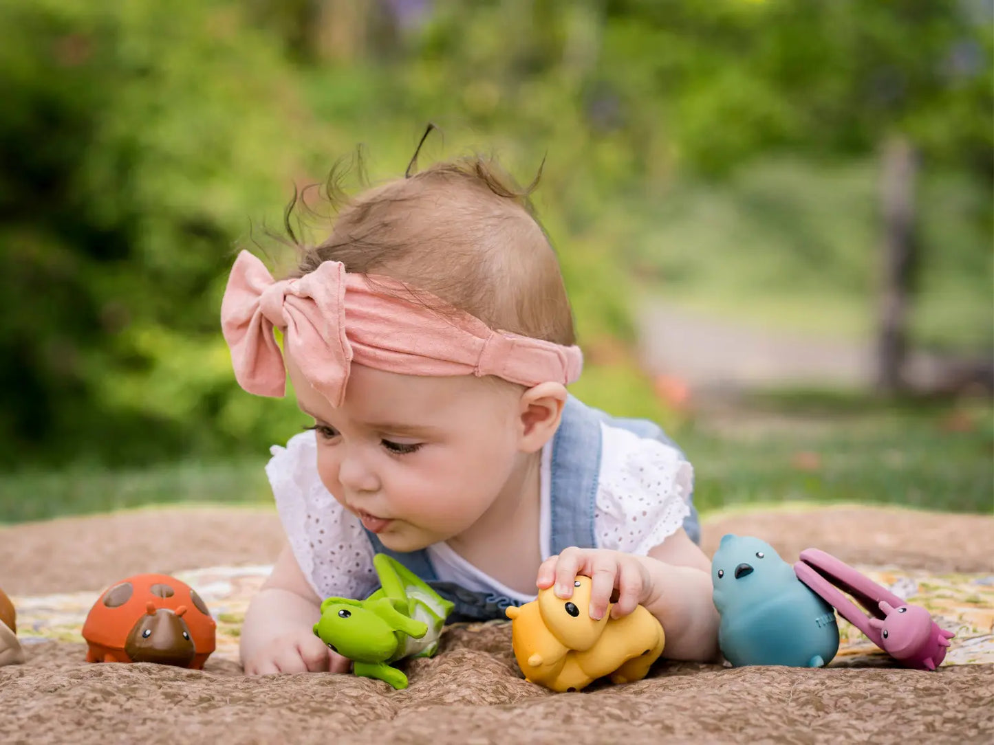 Infant on tummy playing with natural rubber butterfly toy and other sensory toys
