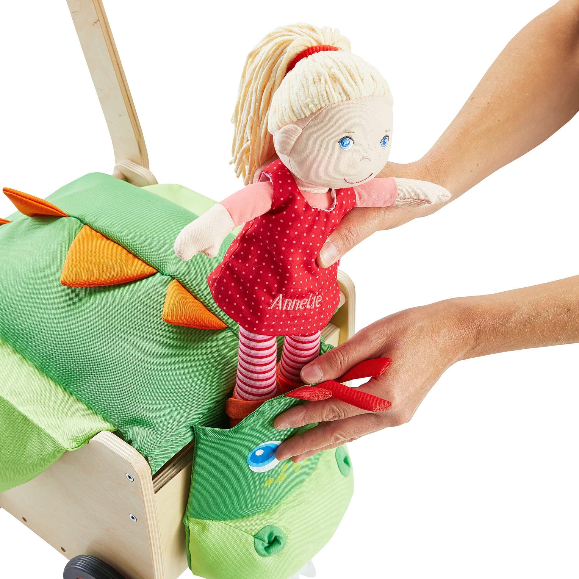 Child's hand placing a doll named 'Annelie' into a green dragon-shaped toy.
