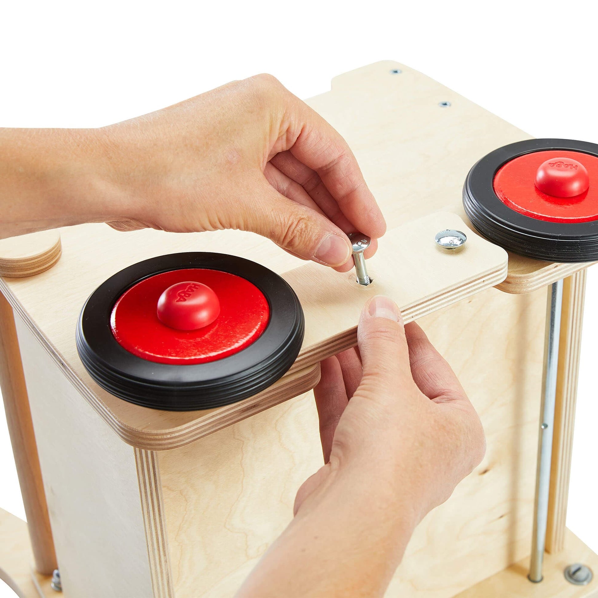 Person assembling a wooden structure with red and black components
