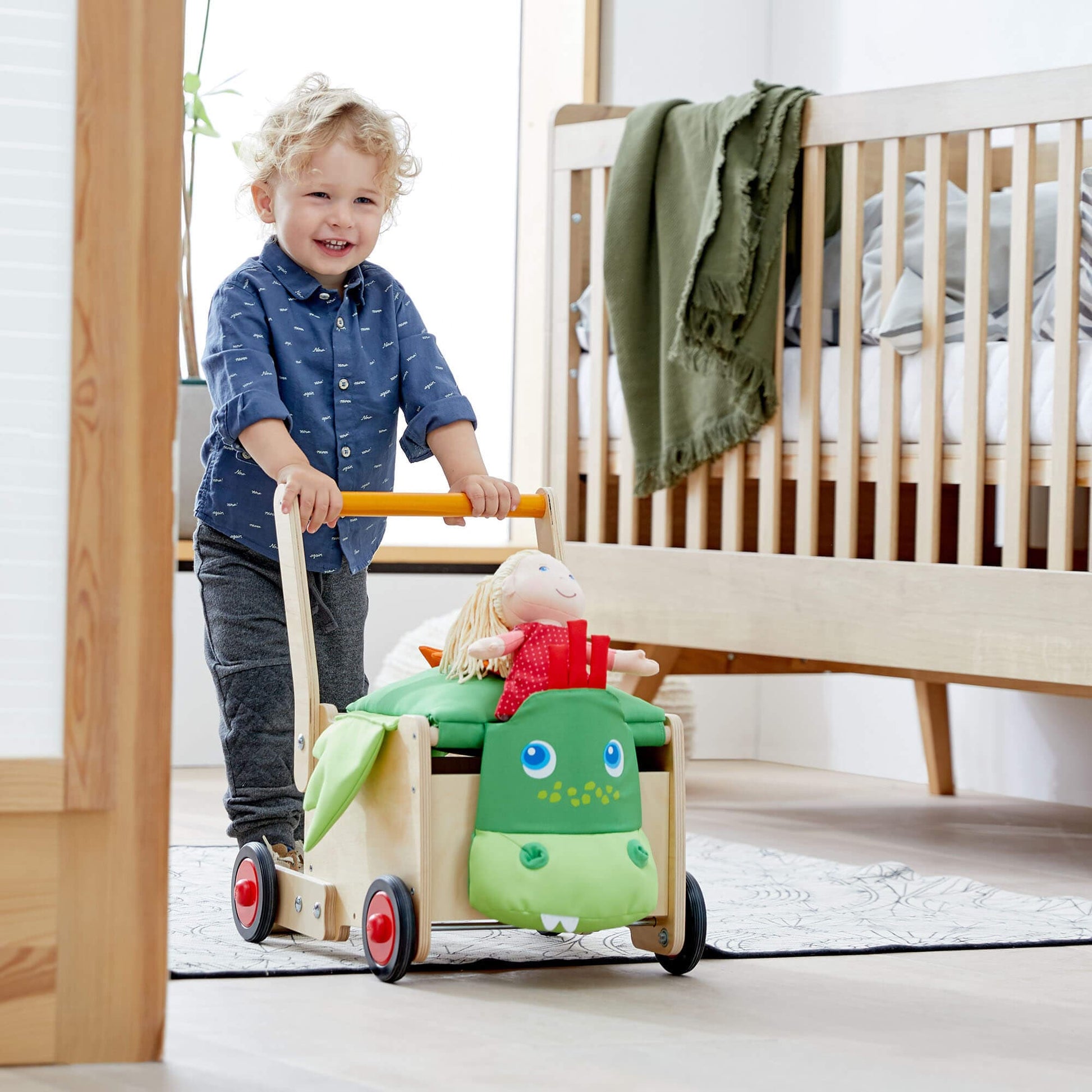 Child pushing a toy cart with a doll in a nursery