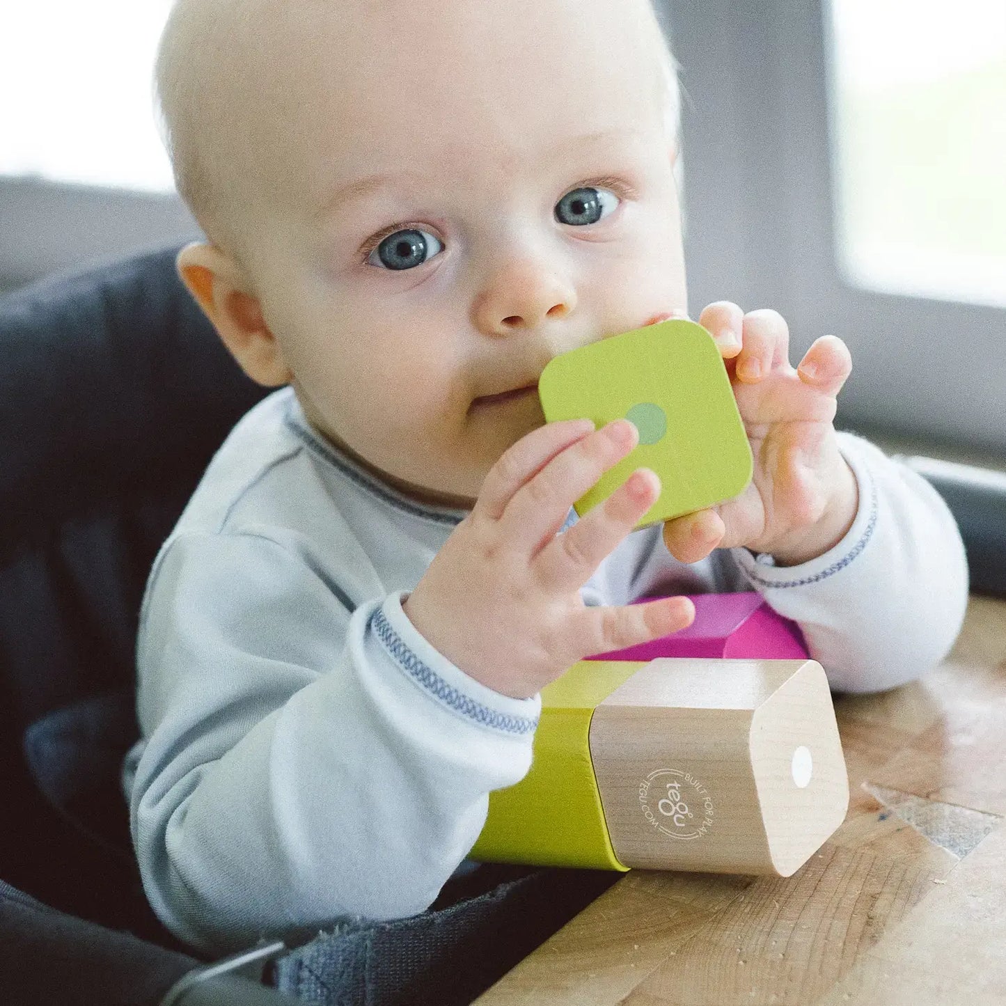 A baby playing with wooden and magnetic blocks by Tegu