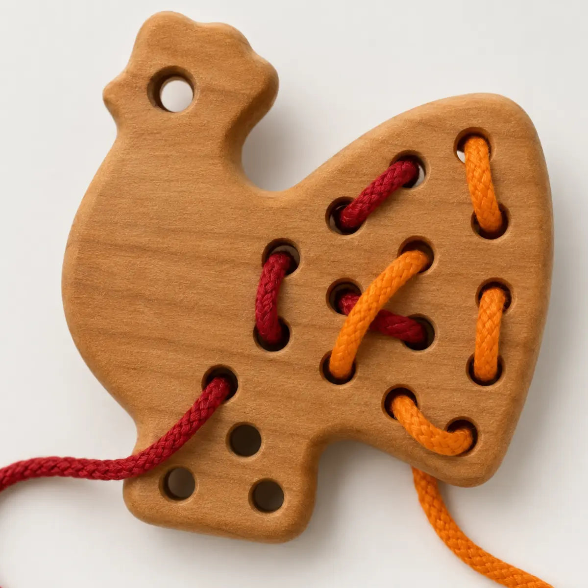 Close-up of BAJO wooden lacing rooster showing cherry wood grain, threading holes, and colorful cords