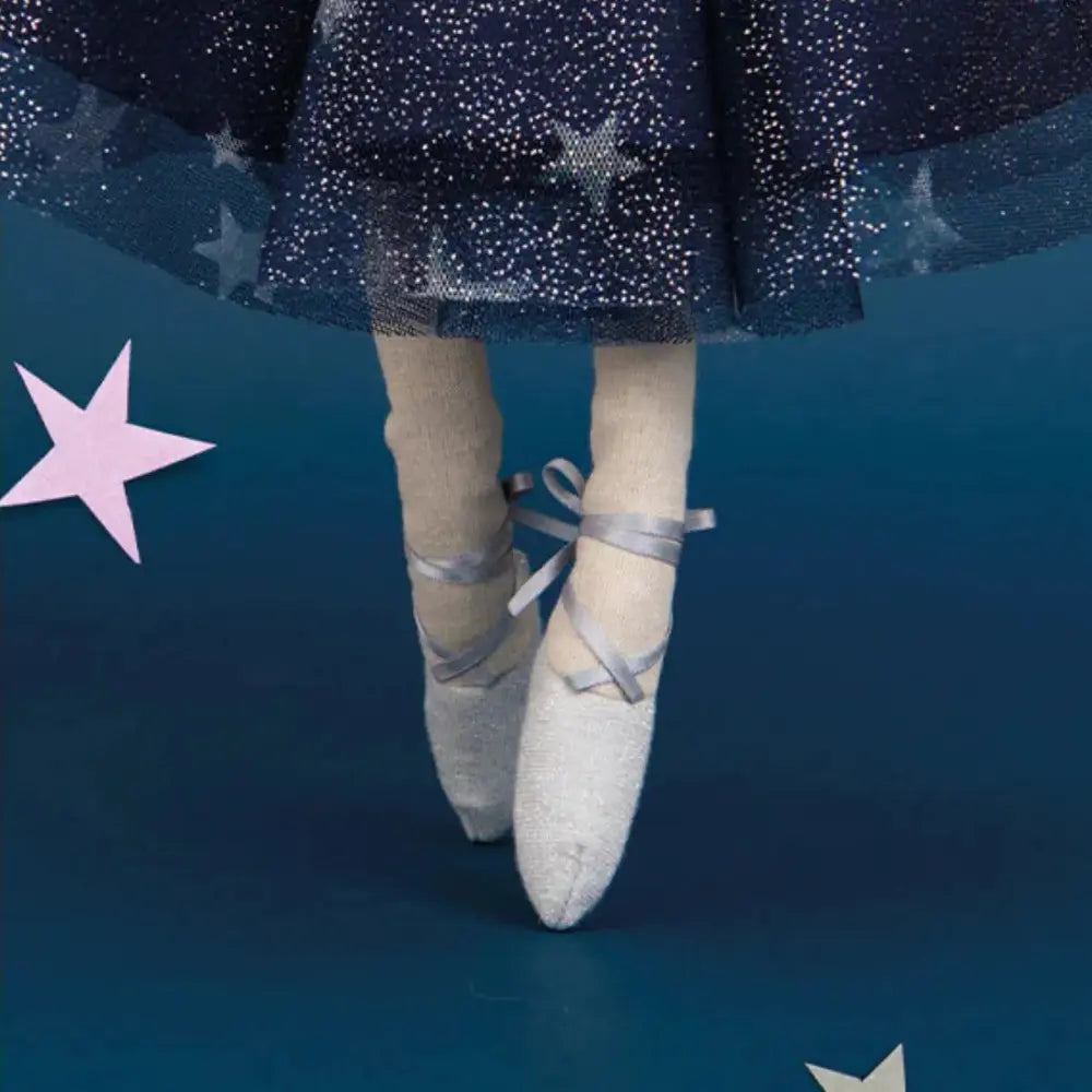 Ballerina doll's feet in pointe shoes with a blue tutu and star decorations on a blue background
