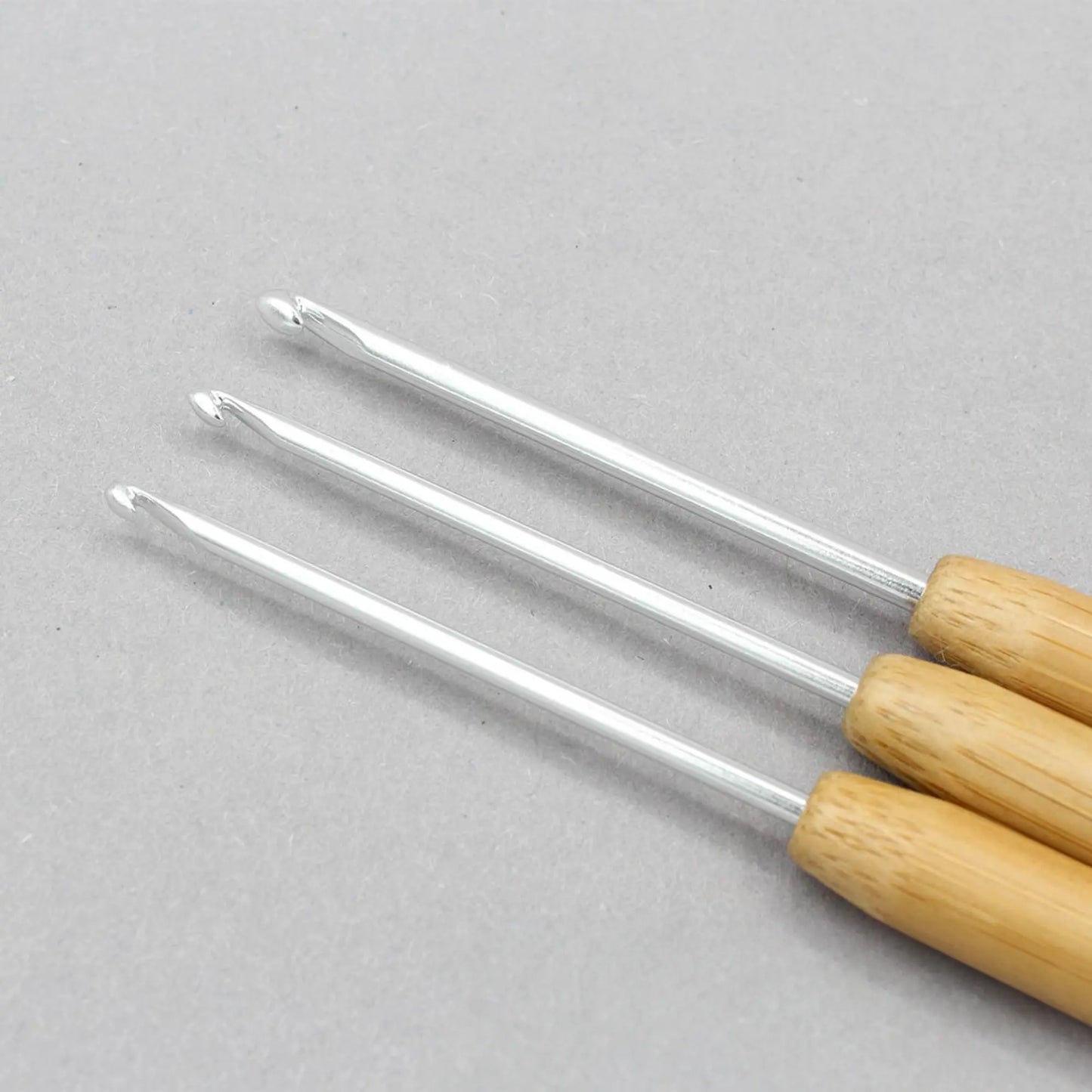 Close-up of fine aluminum crochet hook tips with smooth bamboo handles for detailed crochet work