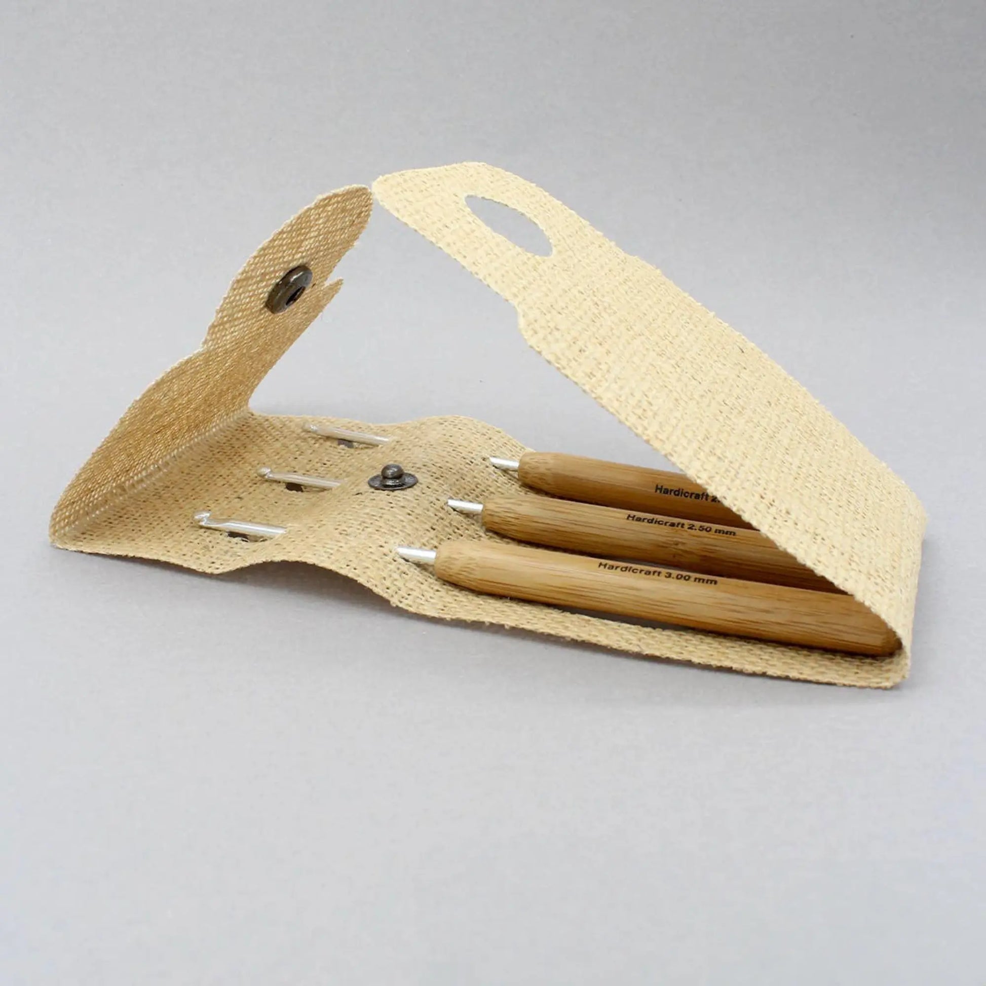 Bamboo handle aluminum crochet hooks stored inside an open natural burlap pouch