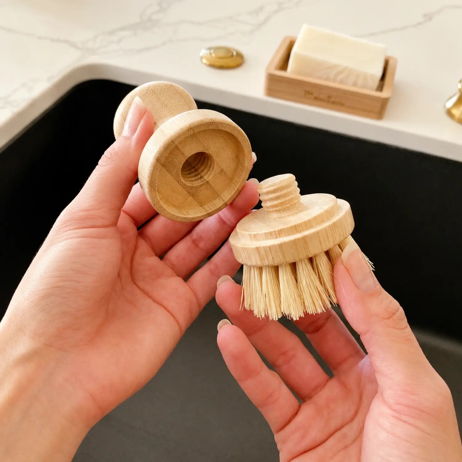 Hands showing the threaded connection between a bamboo dish brush handle and replaceable brush head.