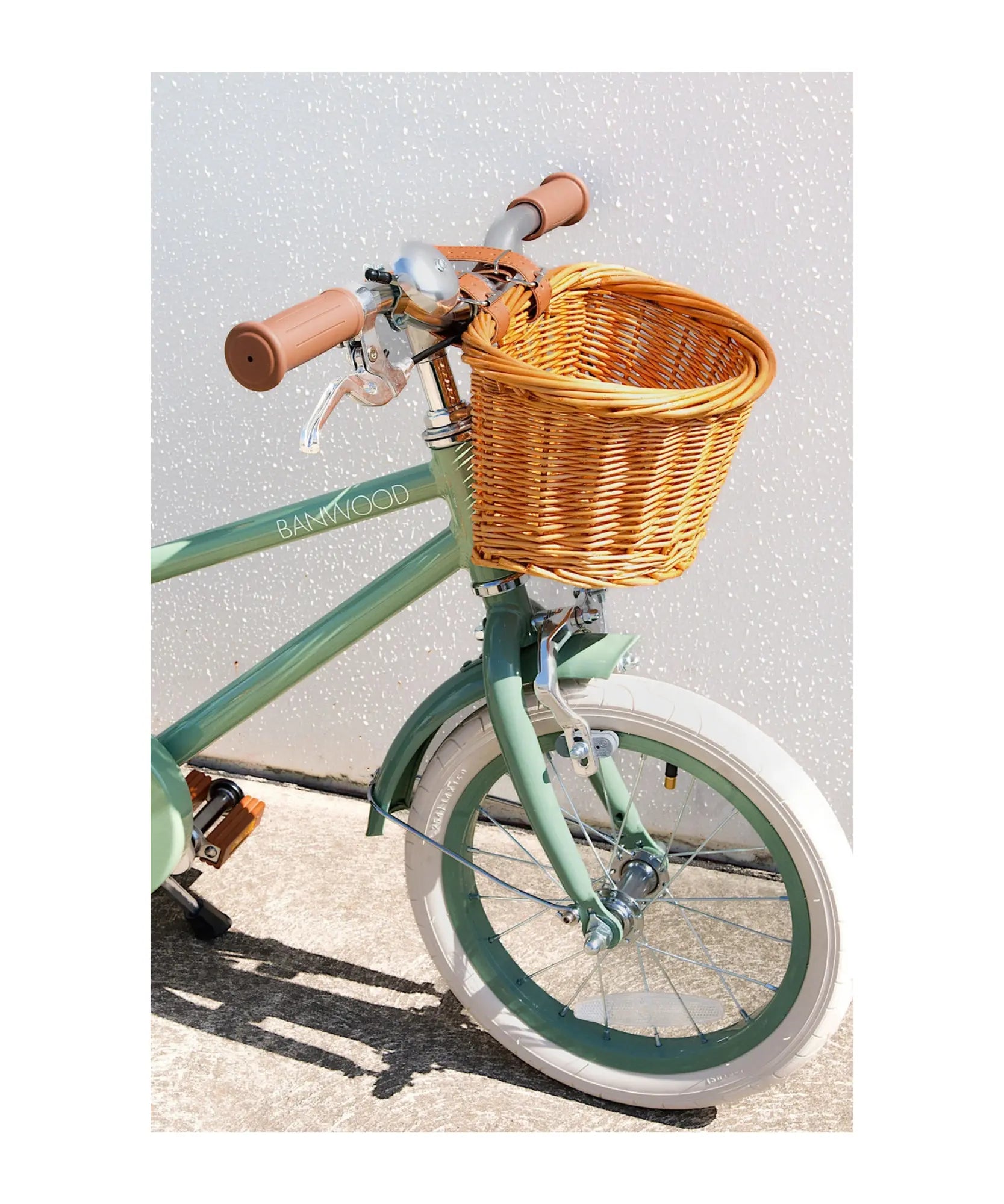 Green bicycle with a wicker basket on a light background