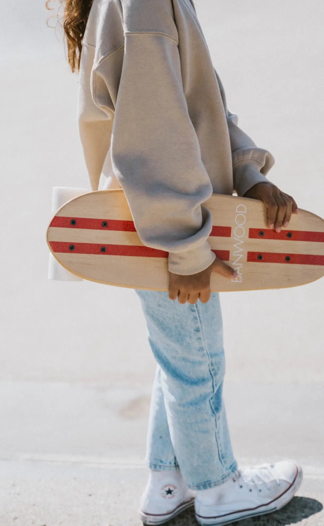 Person holding a skateboard with a red stripe against a white background