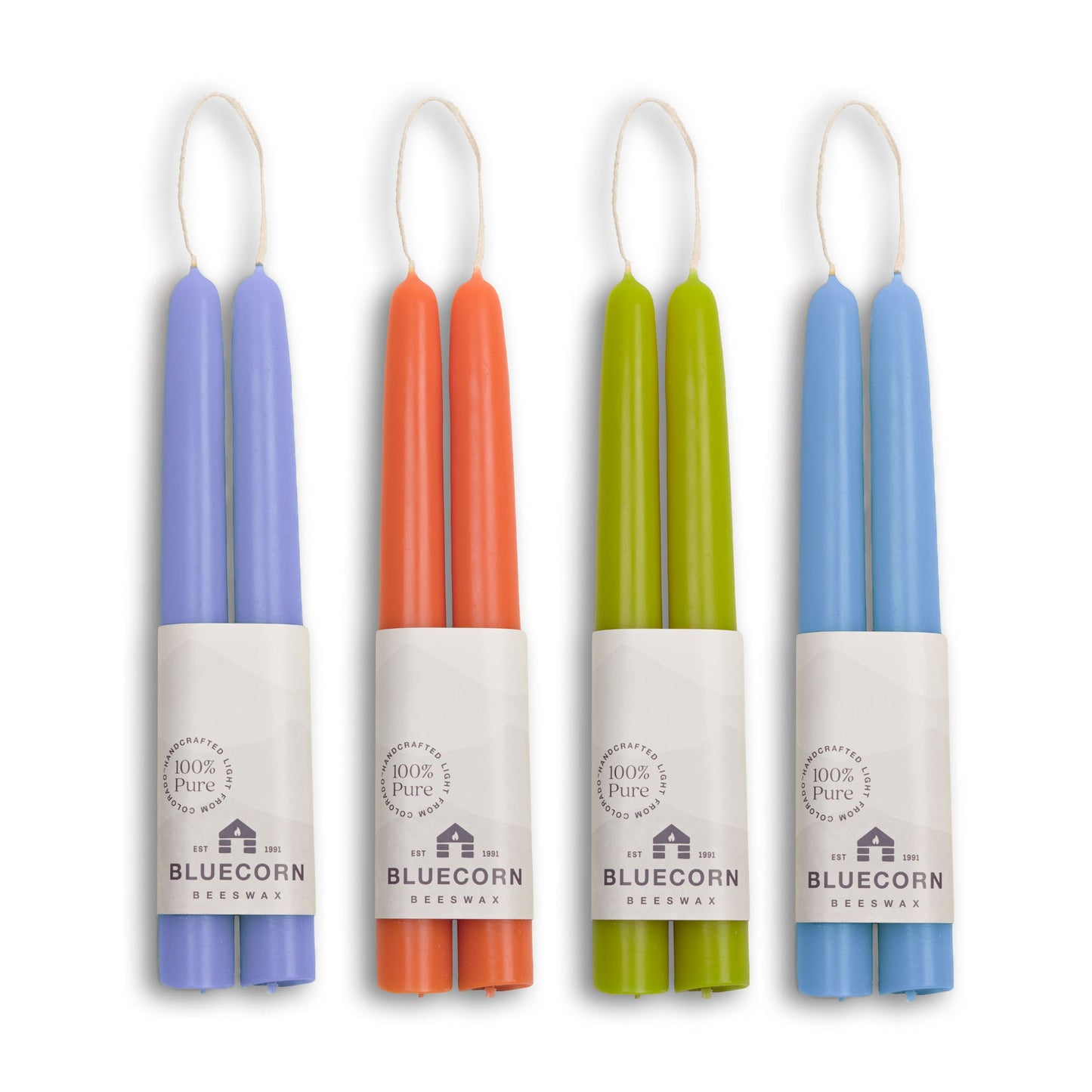 Set of four colorful candles in their packaging with Bluecorn branding.