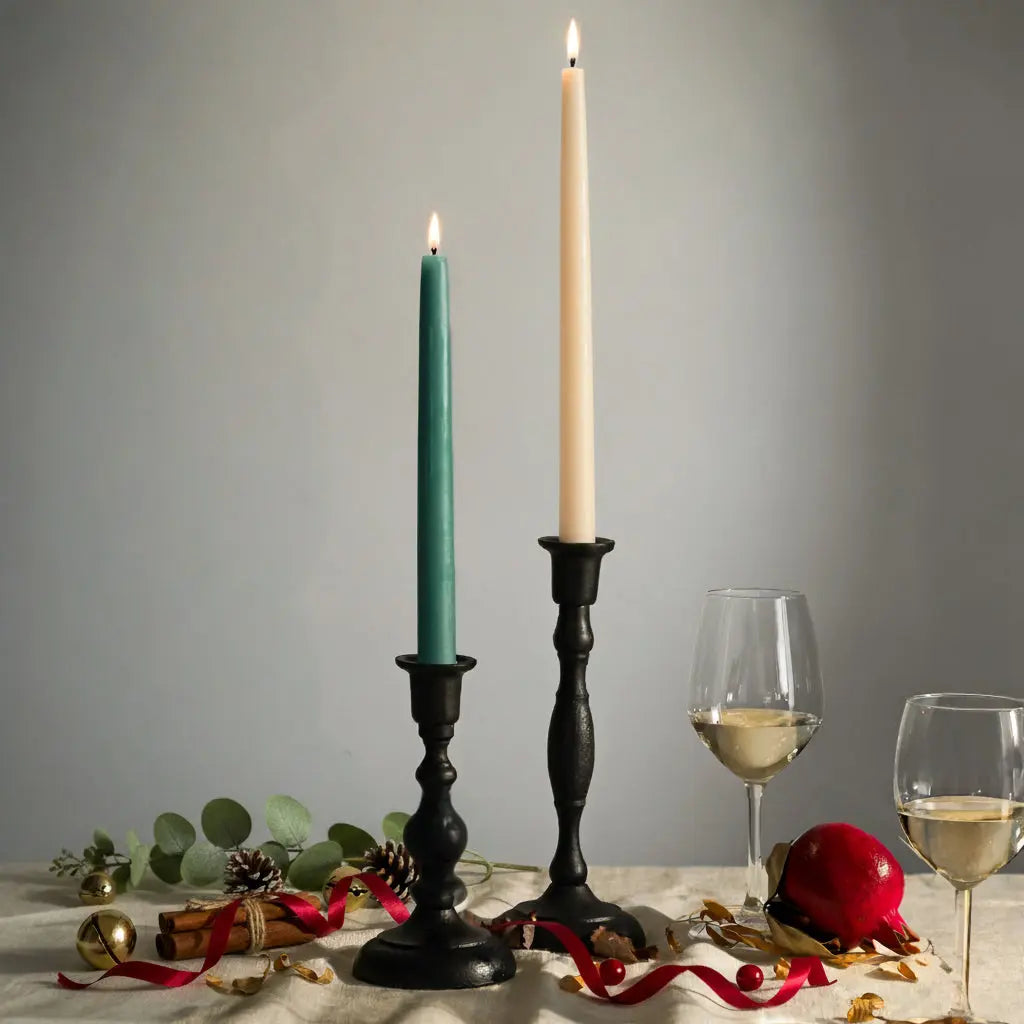 Two candlesticks with lit candles, a glass of wine, and decorative items on a table against a gray background.