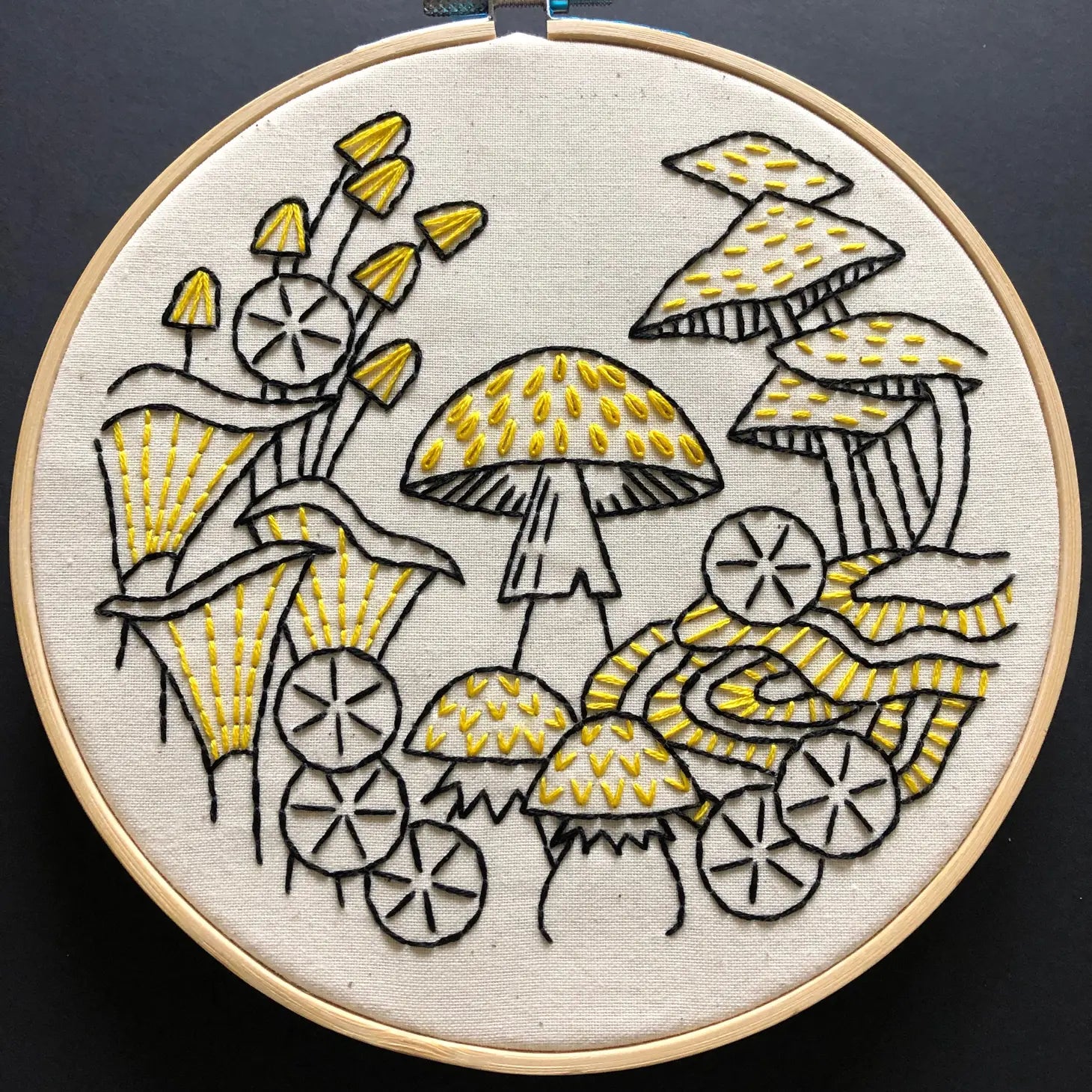 Overview of a finished mushroom embroidery kit on black background