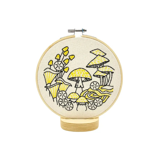 Embroidery hoop with yellow and black mushroom design on a white background