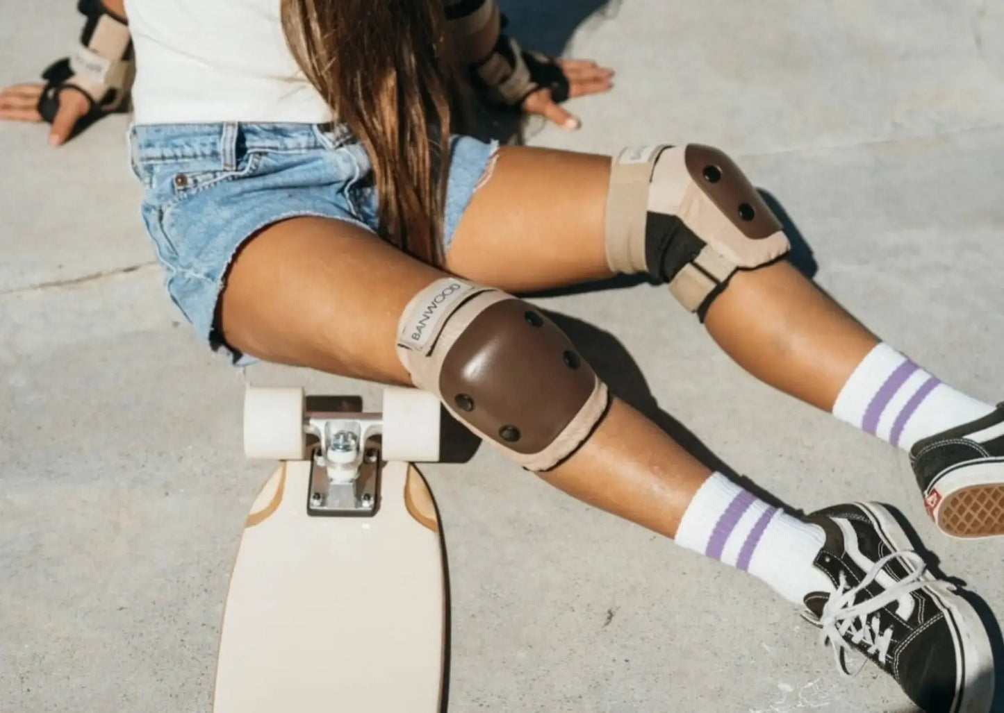 Person riding a skateboard with knee pads on a concrete surface