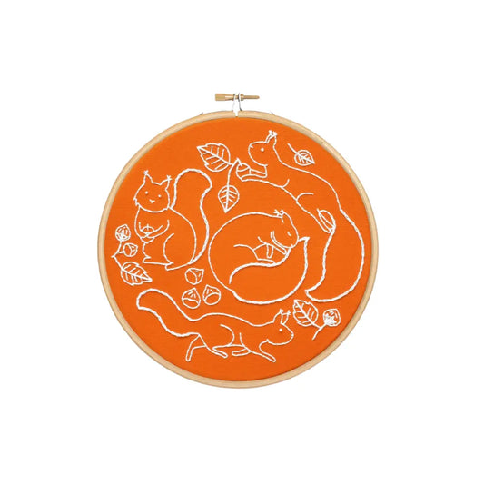 Finished squirrel embroidery hoop with orange fabric, white stitching, acorns, and autumn leaves