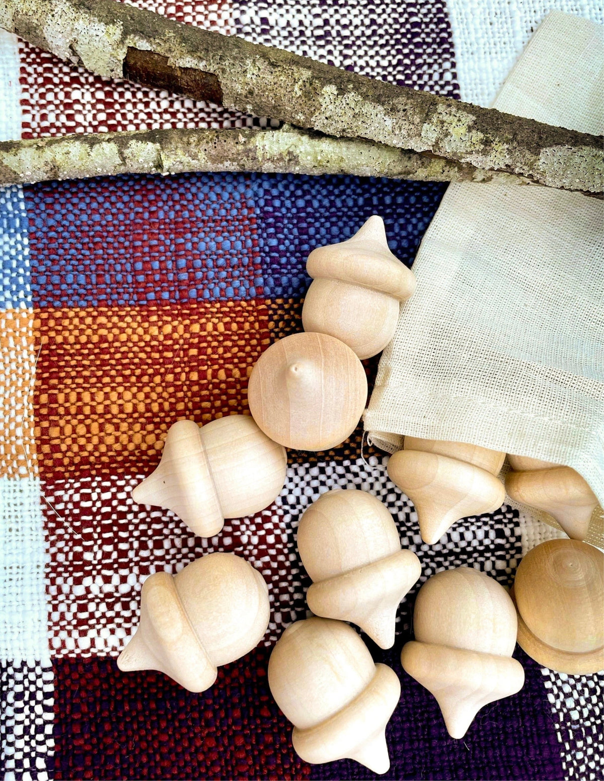 Unfinished wooden acorns arranged on colorful woven fabric