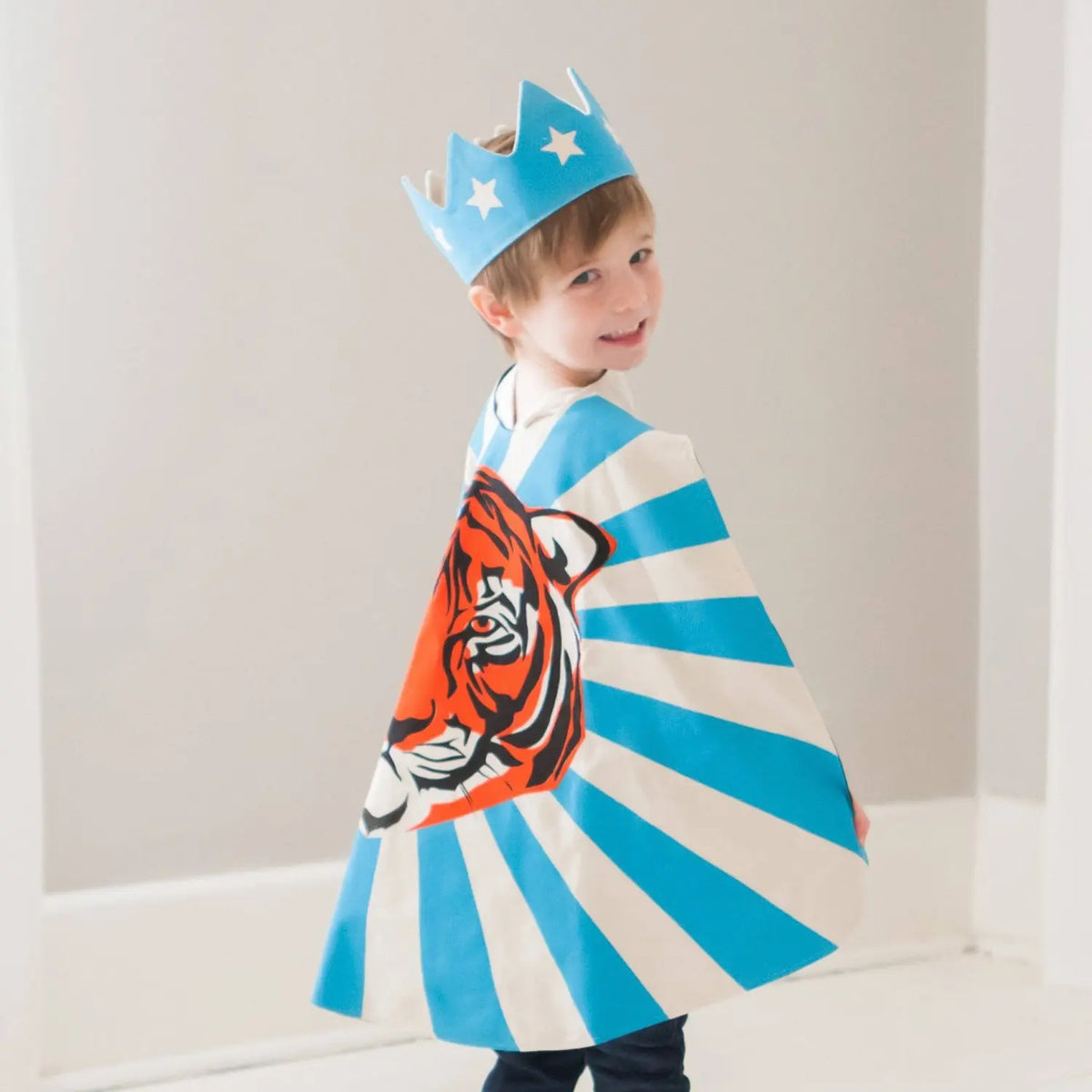 Child wearing a blue cotton canvas star crown with a tiger dress-up cape