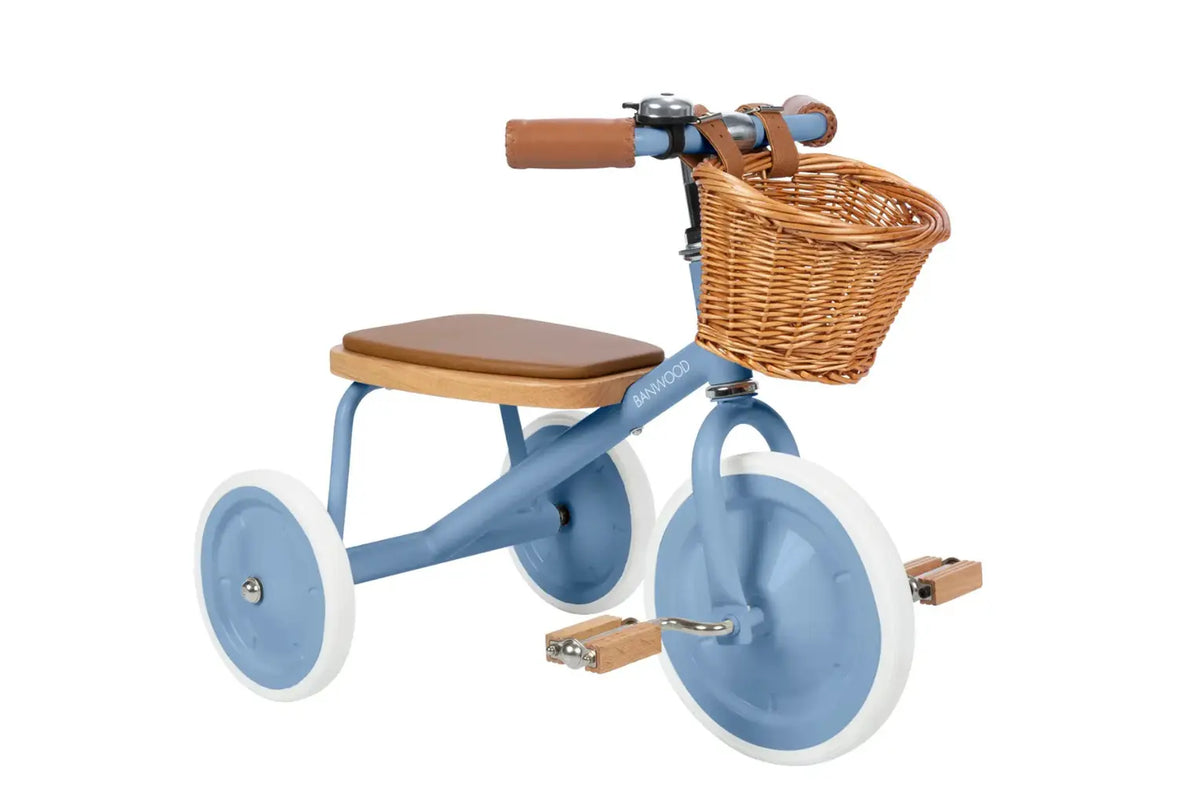 Blue children's tricycle with a brown seat and wicker basket on a white background